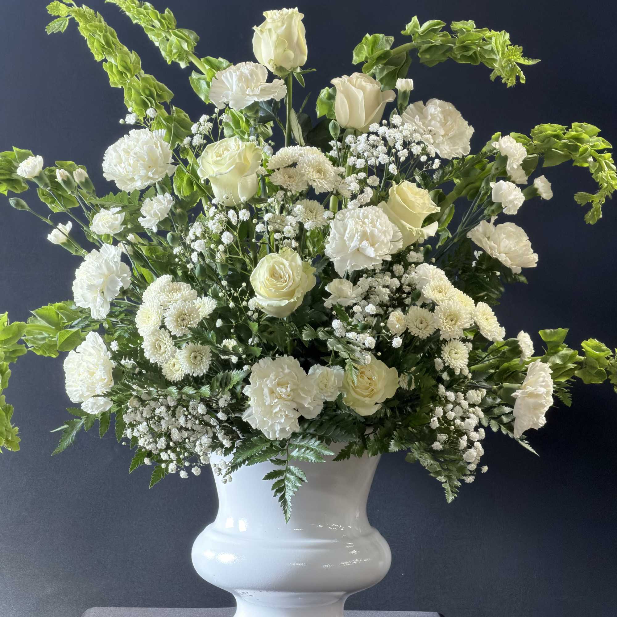 White floral arrangement in a white urn vase