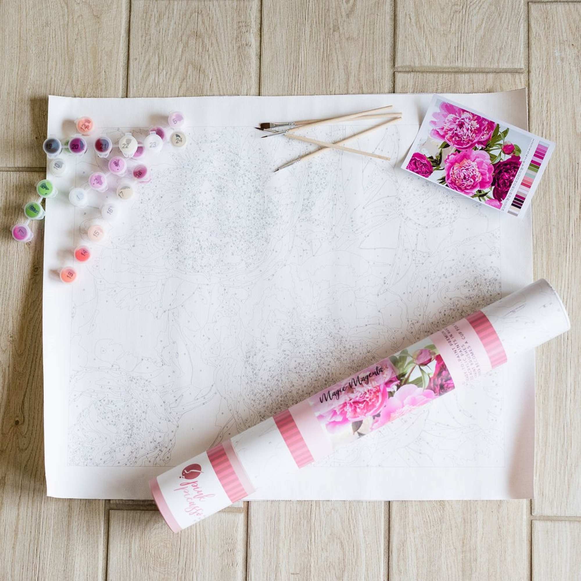 Paint-by-number floral canvas with paint pots, brushes, and reference card