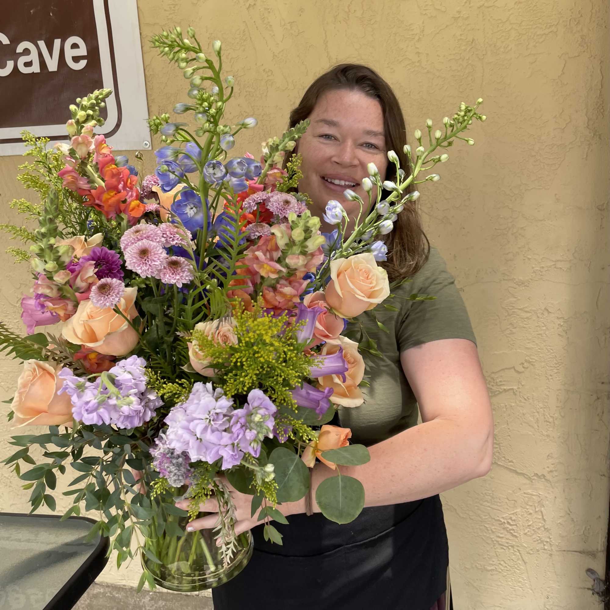 Large mixed bouquet with peach roses and lavender flowers in a glass vase