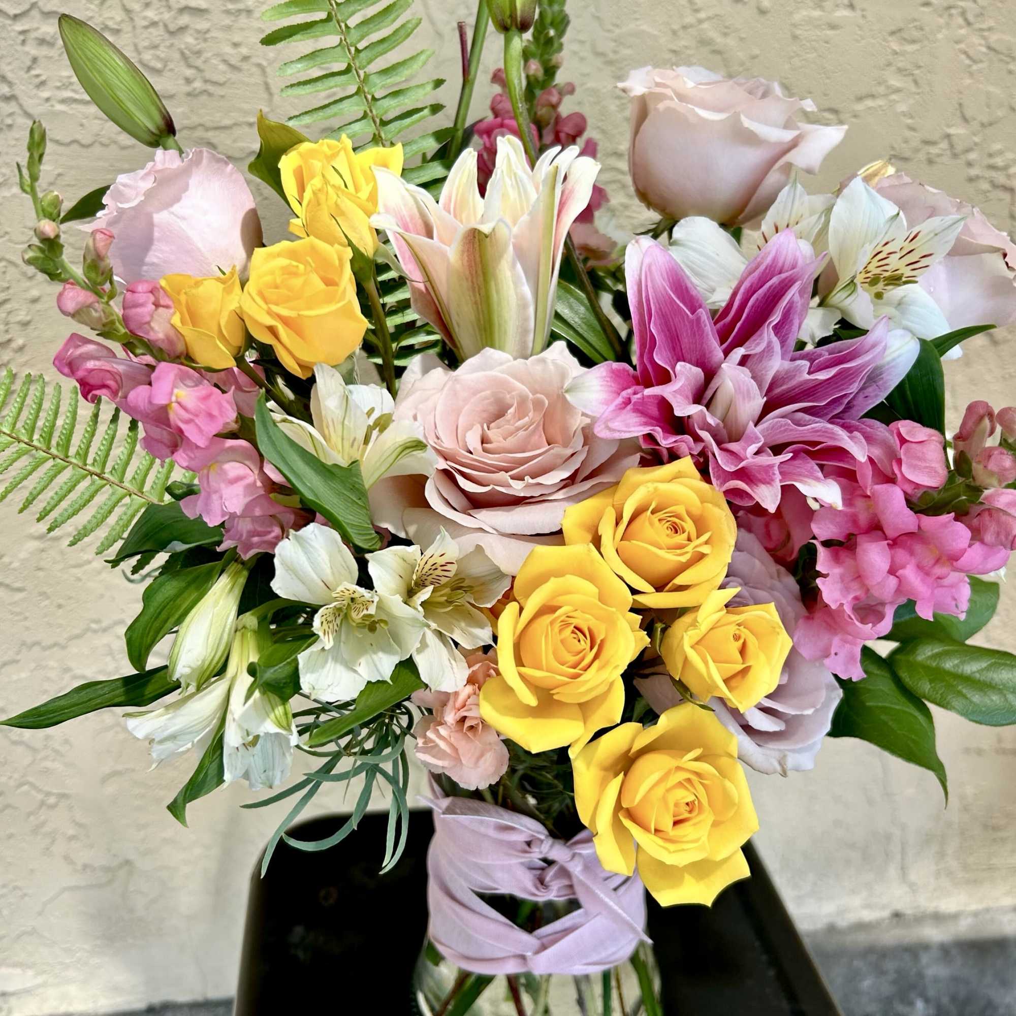 Mixed bouquet of yellow and pink roses with lilies in a glass vase