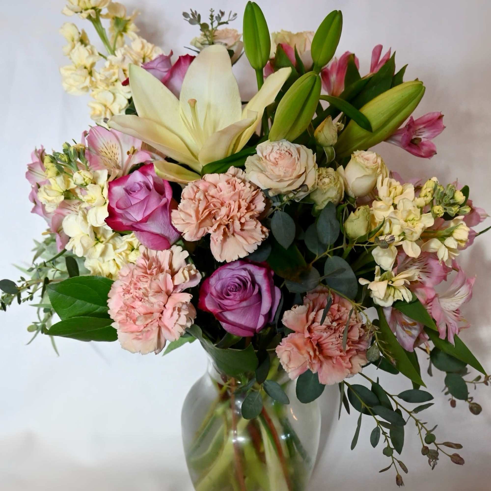 Mixed bouquet of lilies, roses, and carnations in a glass vase