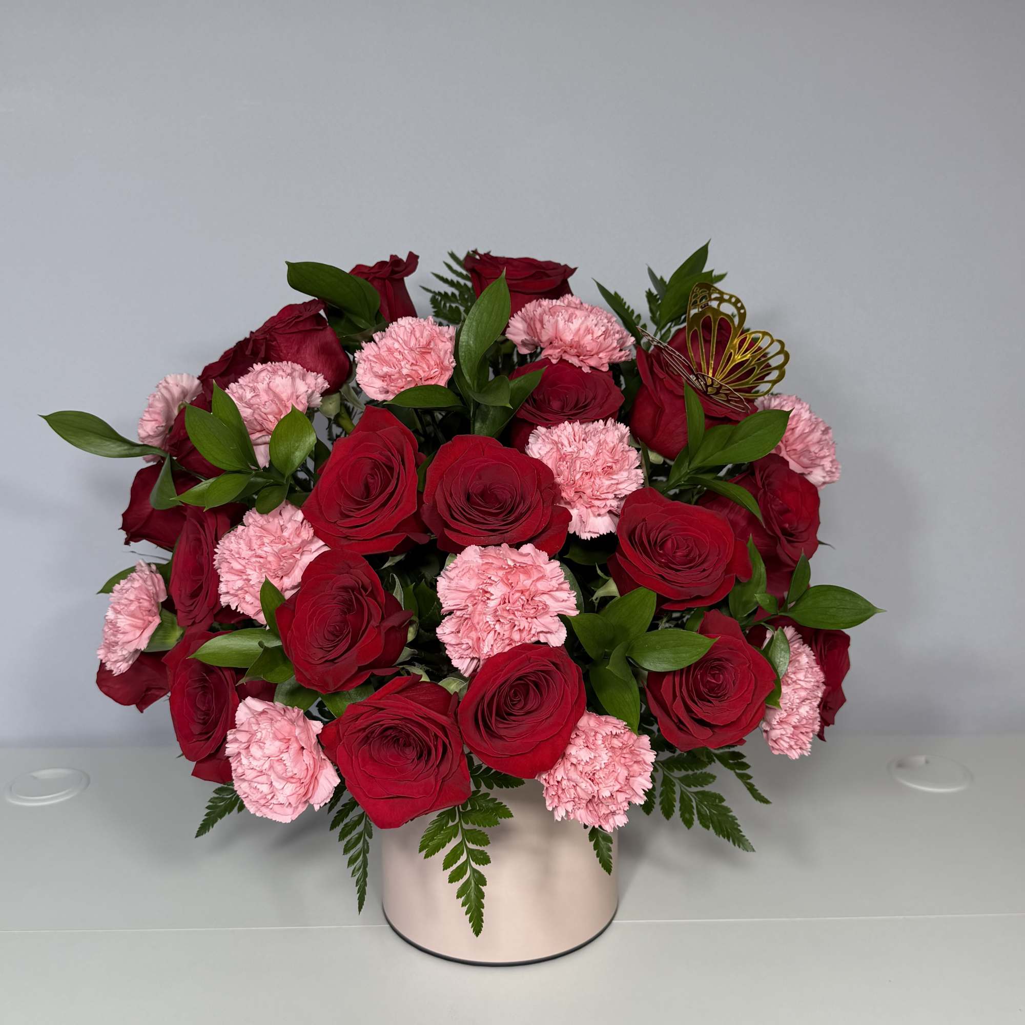 A beautiful and elegant arrangement of red roses and carnations, beautifully presented