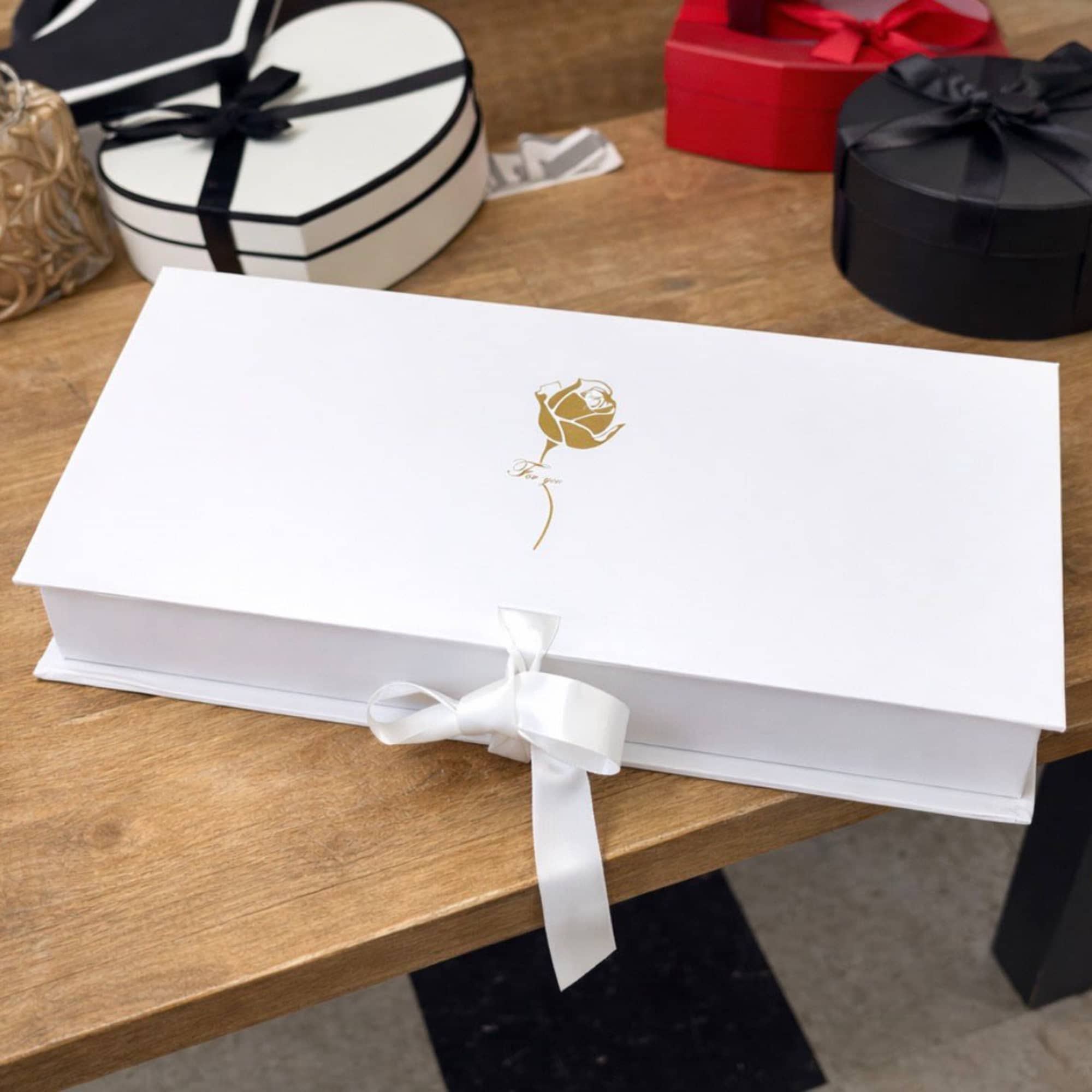 White gift box with a gold rose emblem and ribbon bow