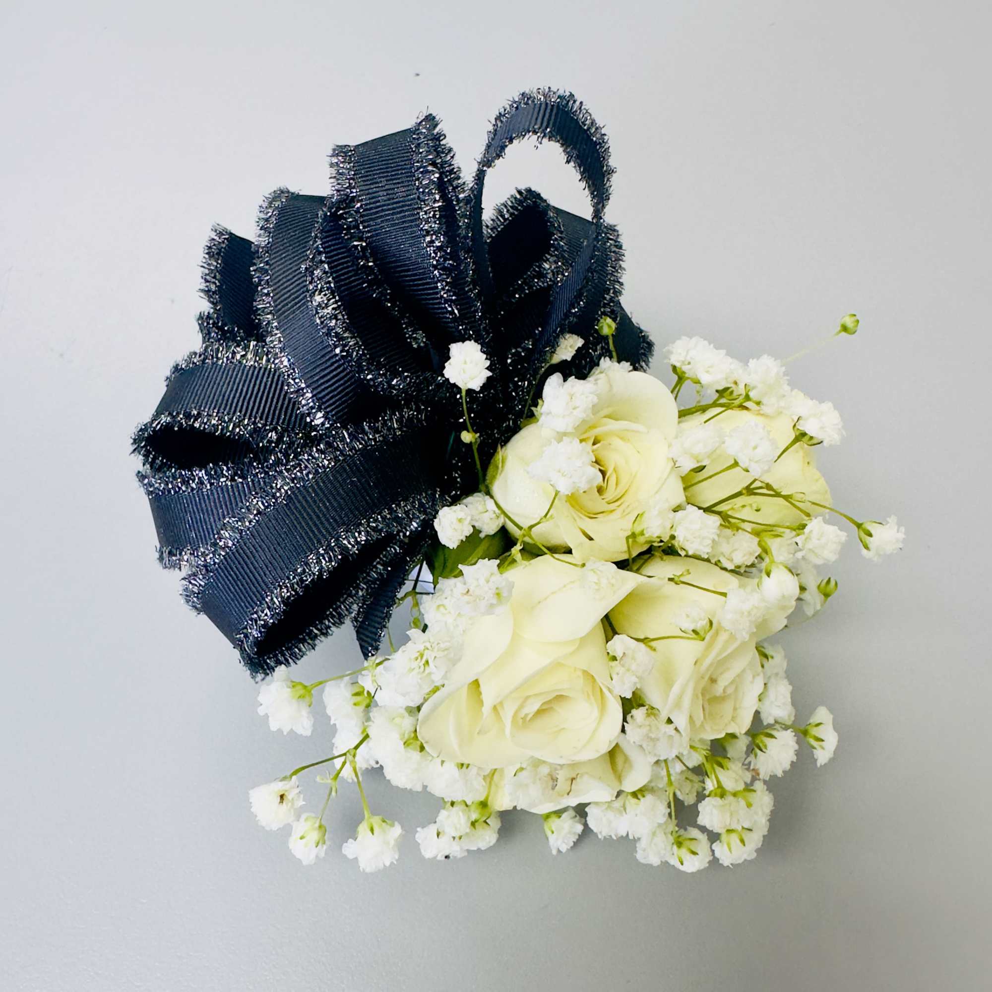 Creamy white roses clustered into a compact, hand-tied corsage give this wrist