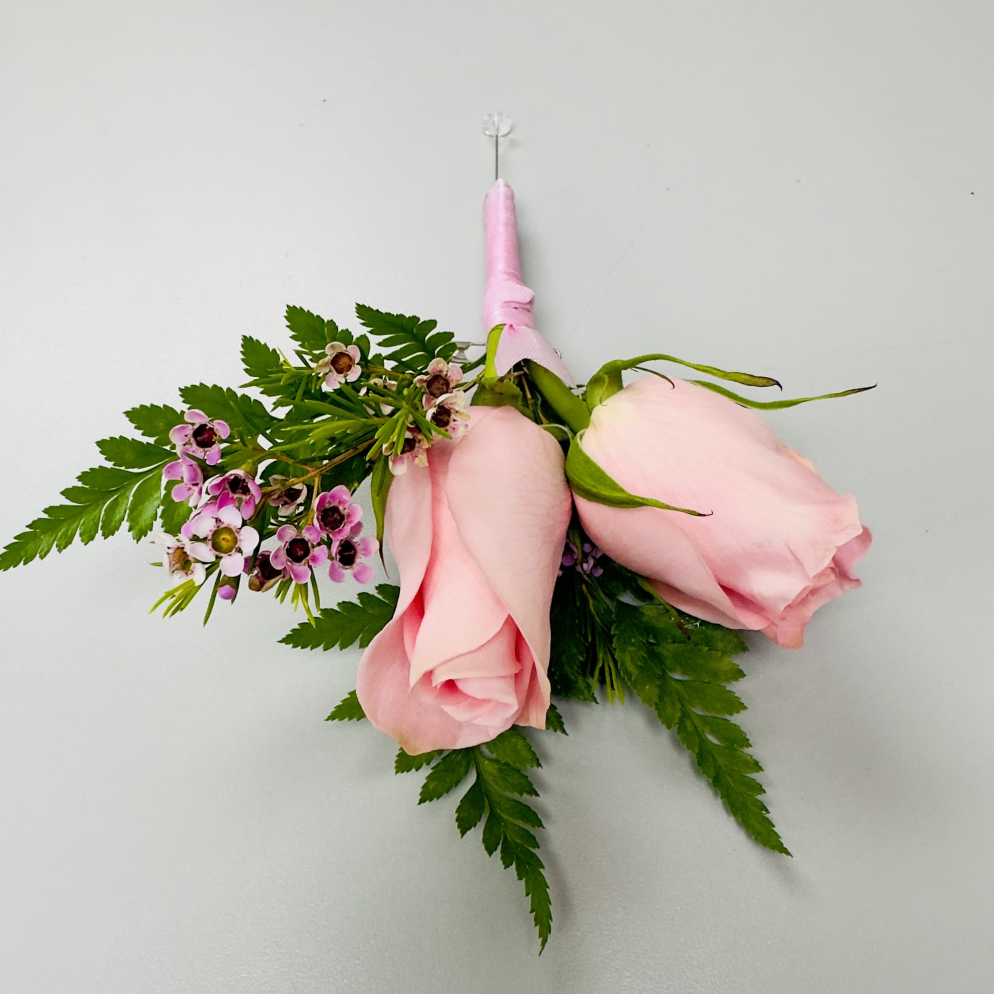 A soft pink rose and a matching rosebud form the romantic focal