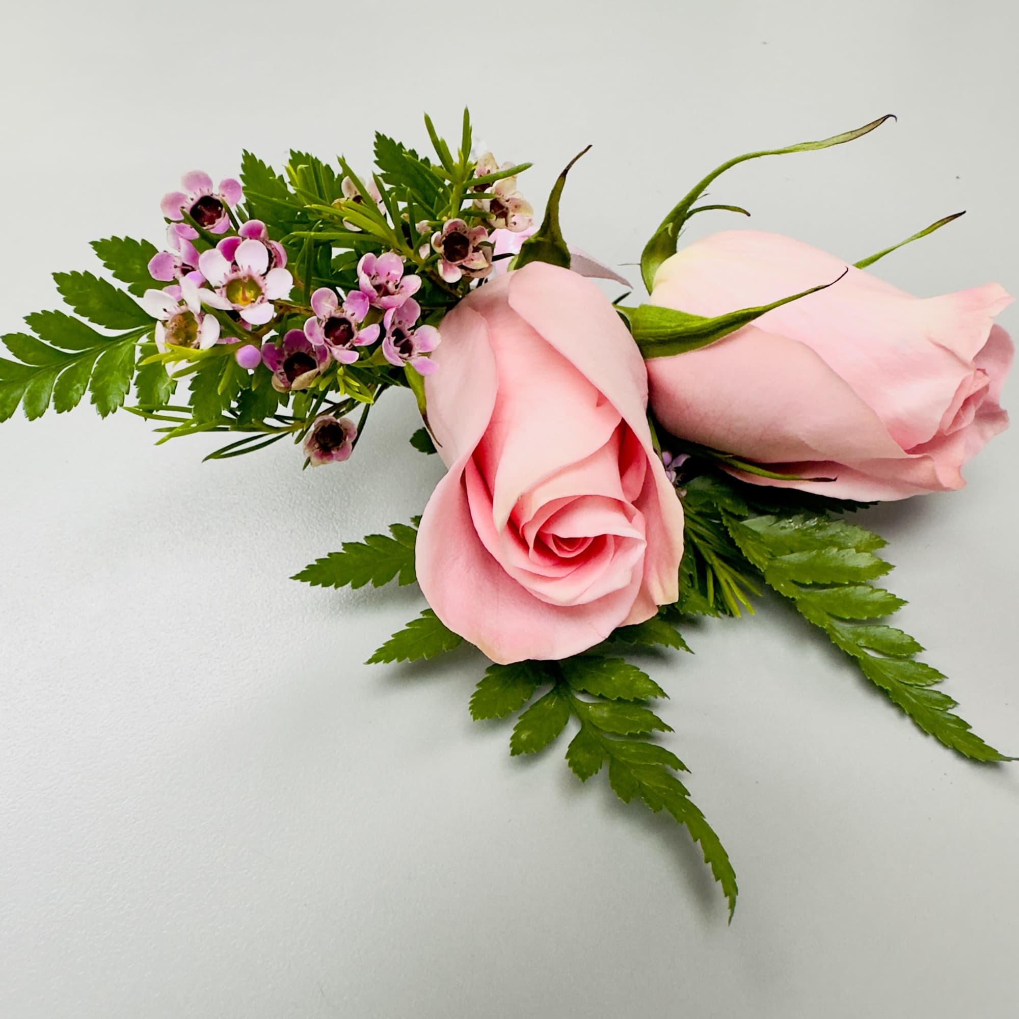 A soft pink rose and a matching rosebud form the romantic focal
