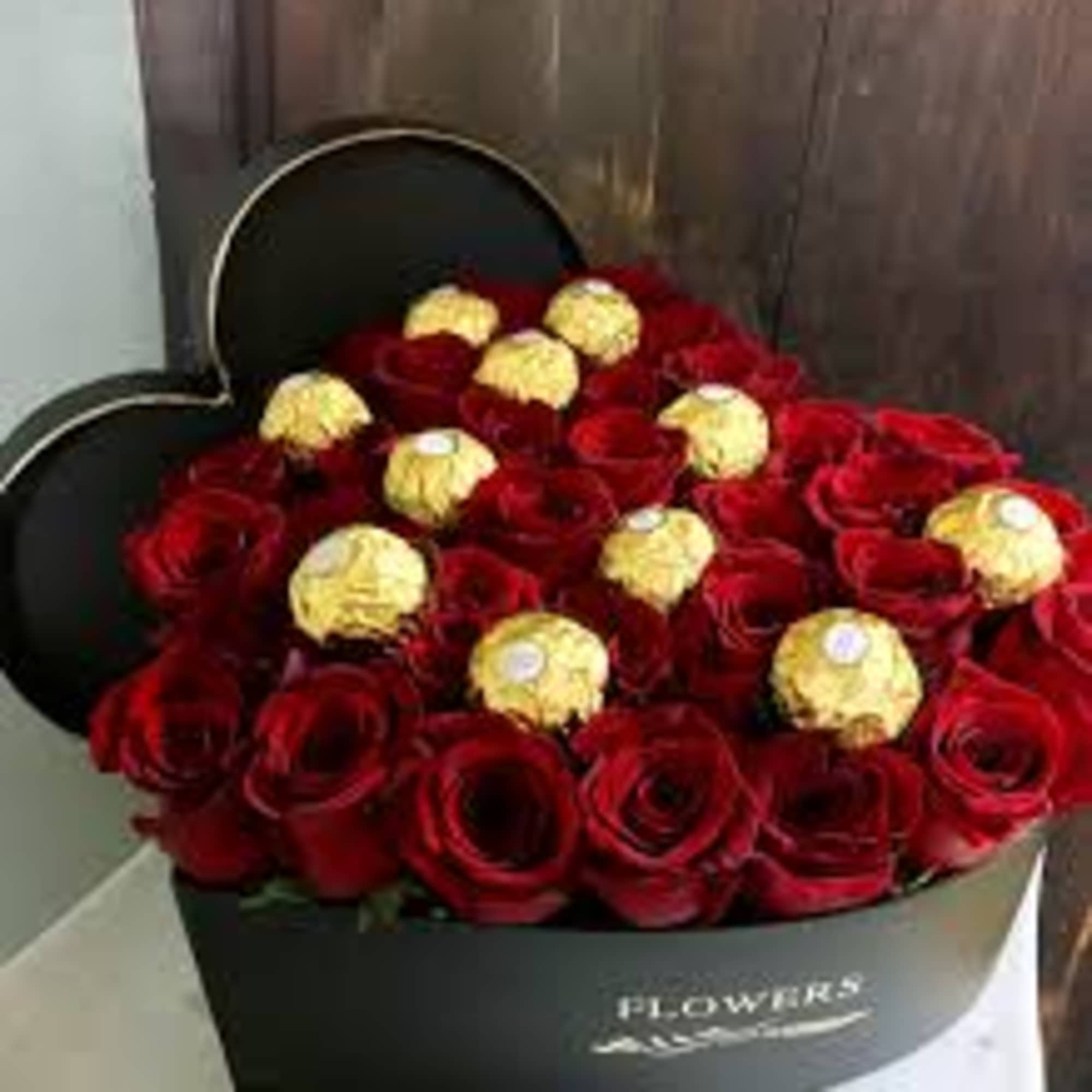 Heart-shaped box filled with red roses and gold-wrapped chocolates