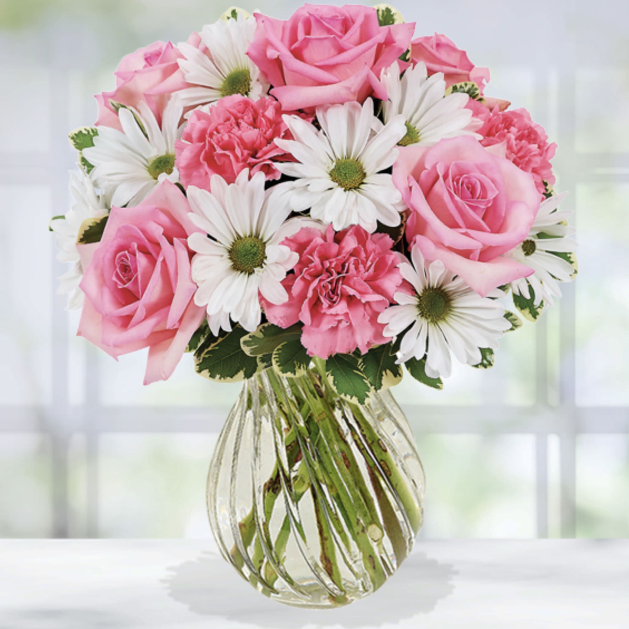 Pink roses and white daisies in a clear glass vase