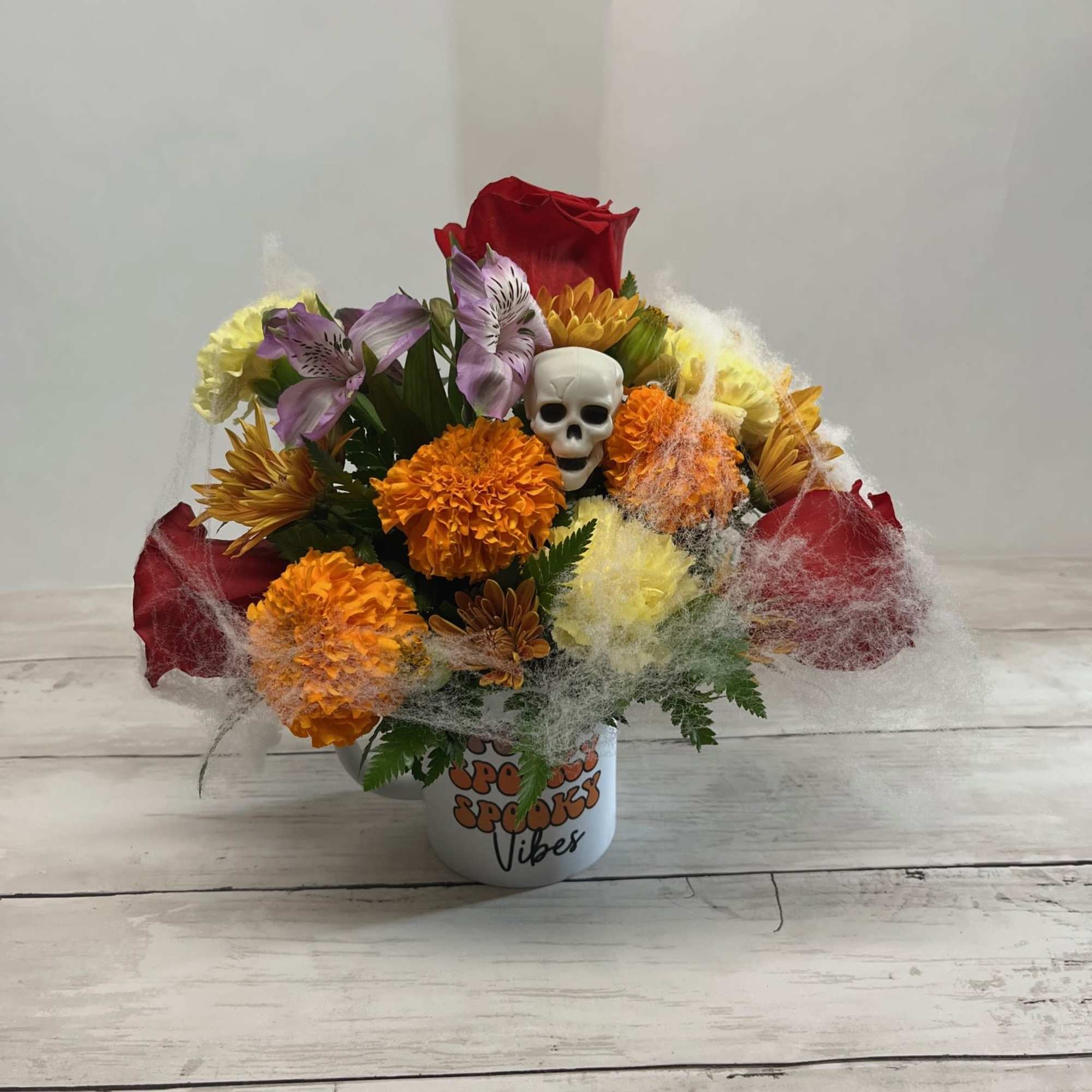 Bouquet of mixed flowers with a skull decoration in a white mug