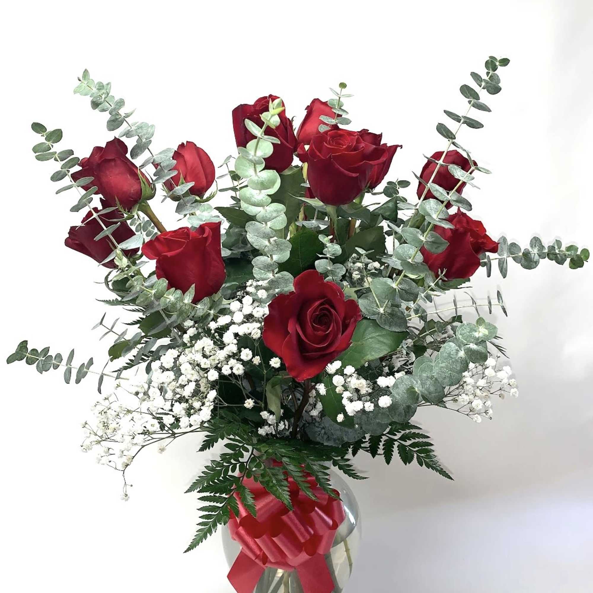 Red roses with baby's breath and eucalyptus in a glass vase with a red ribbon