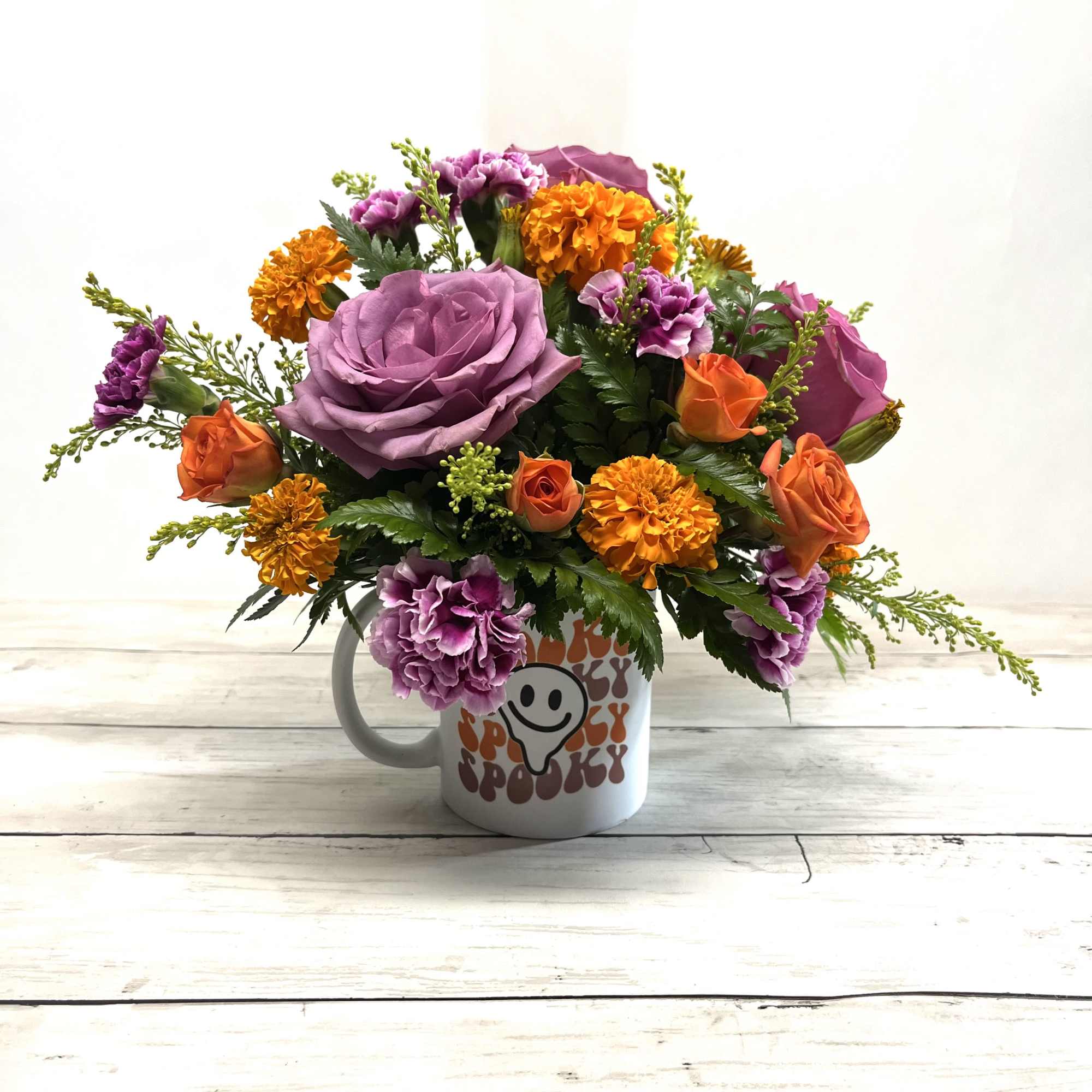 Bouquet of purple and orange flowers in a white mug