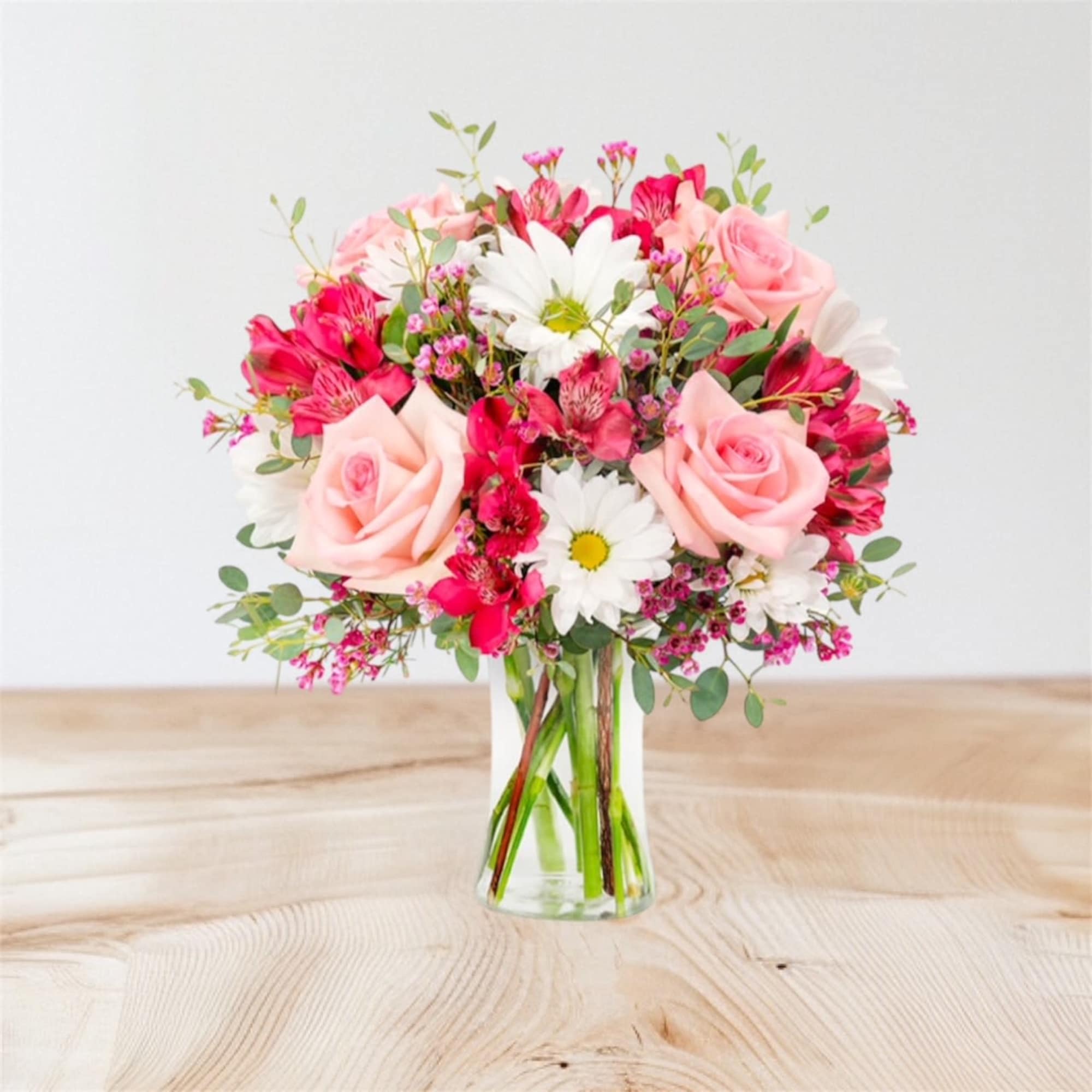 Pink roses and white daisies in a clear glass vase