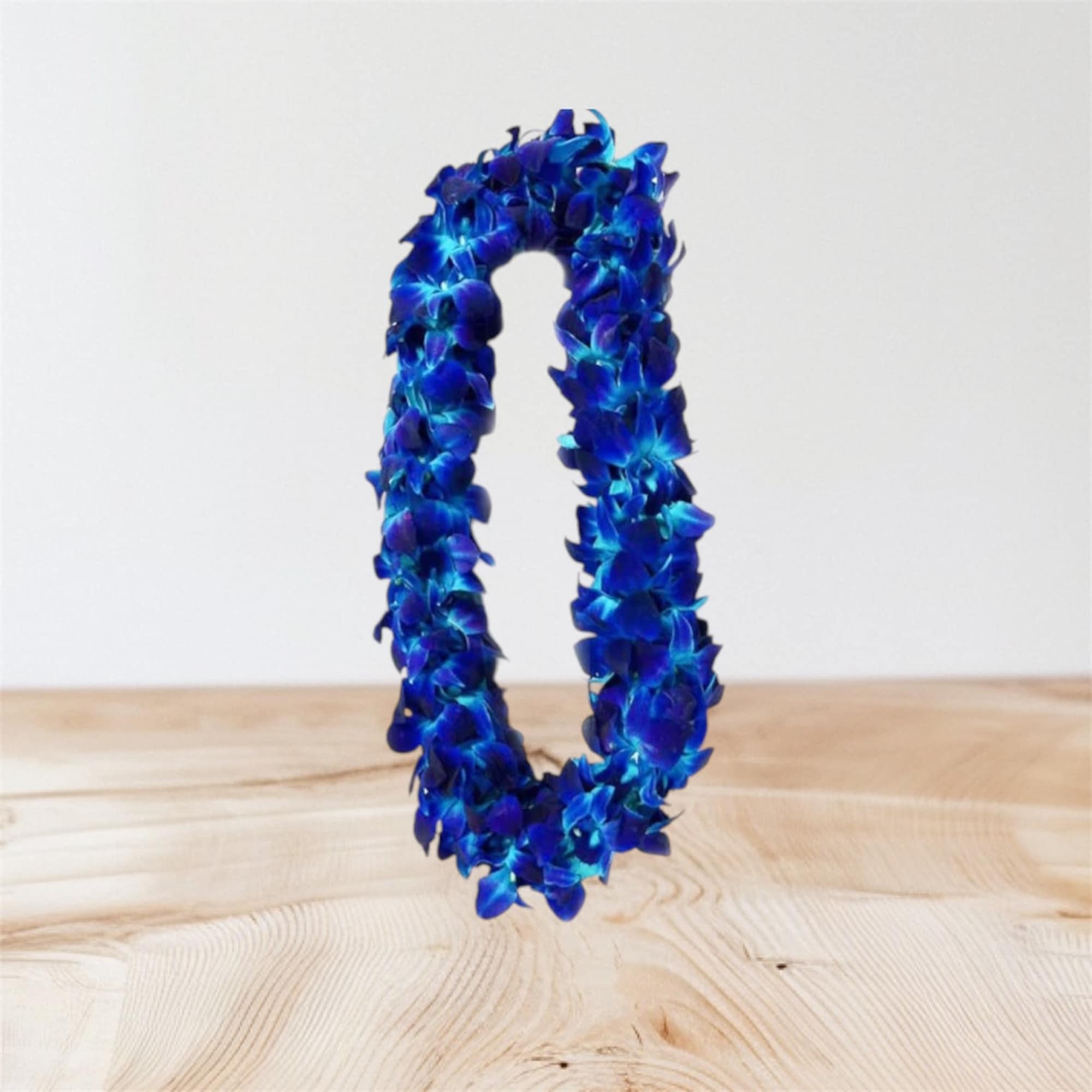 Blue floral lei on a light wood surface