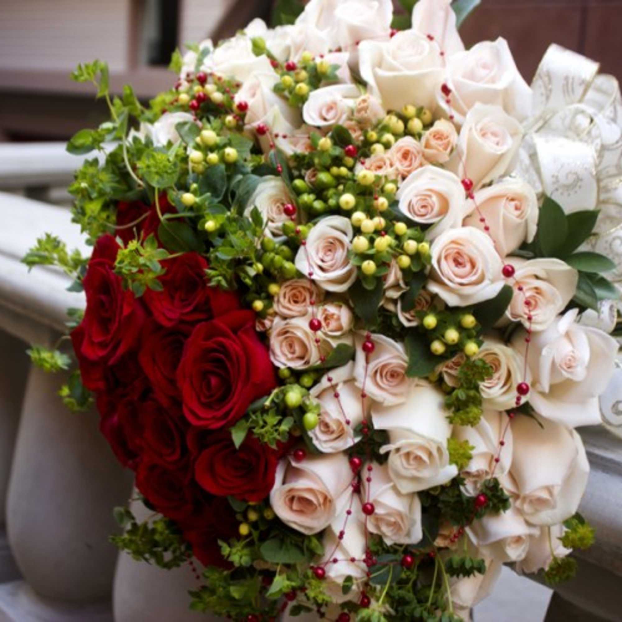 Bouquet of red and ivory roses with berries and ribbon