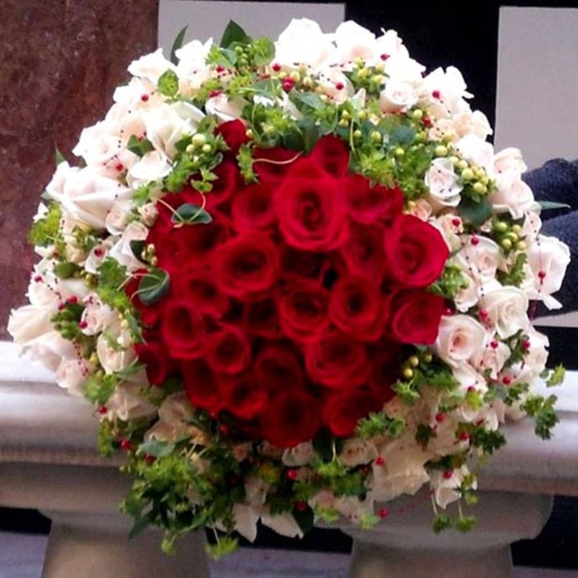 Round bouquet of red and white roses with greenery