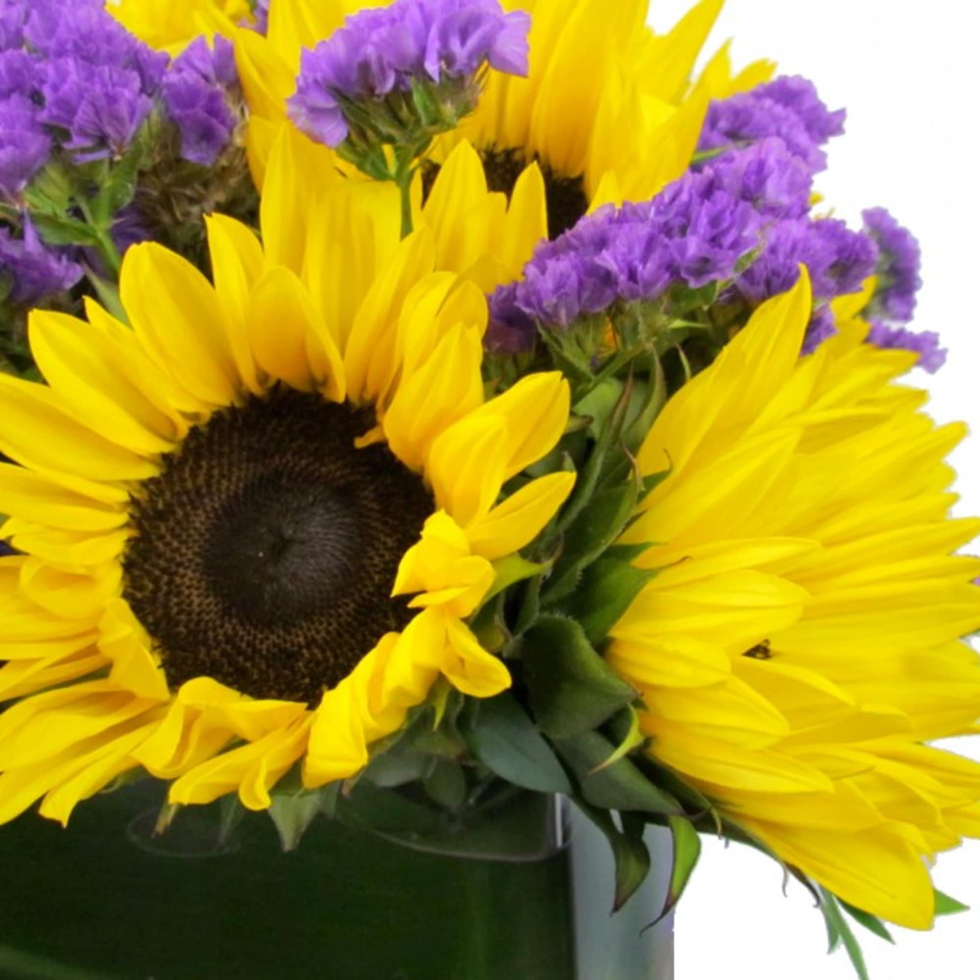 Yellow sunflower arrangement with purple accent flowers in a low clear vase