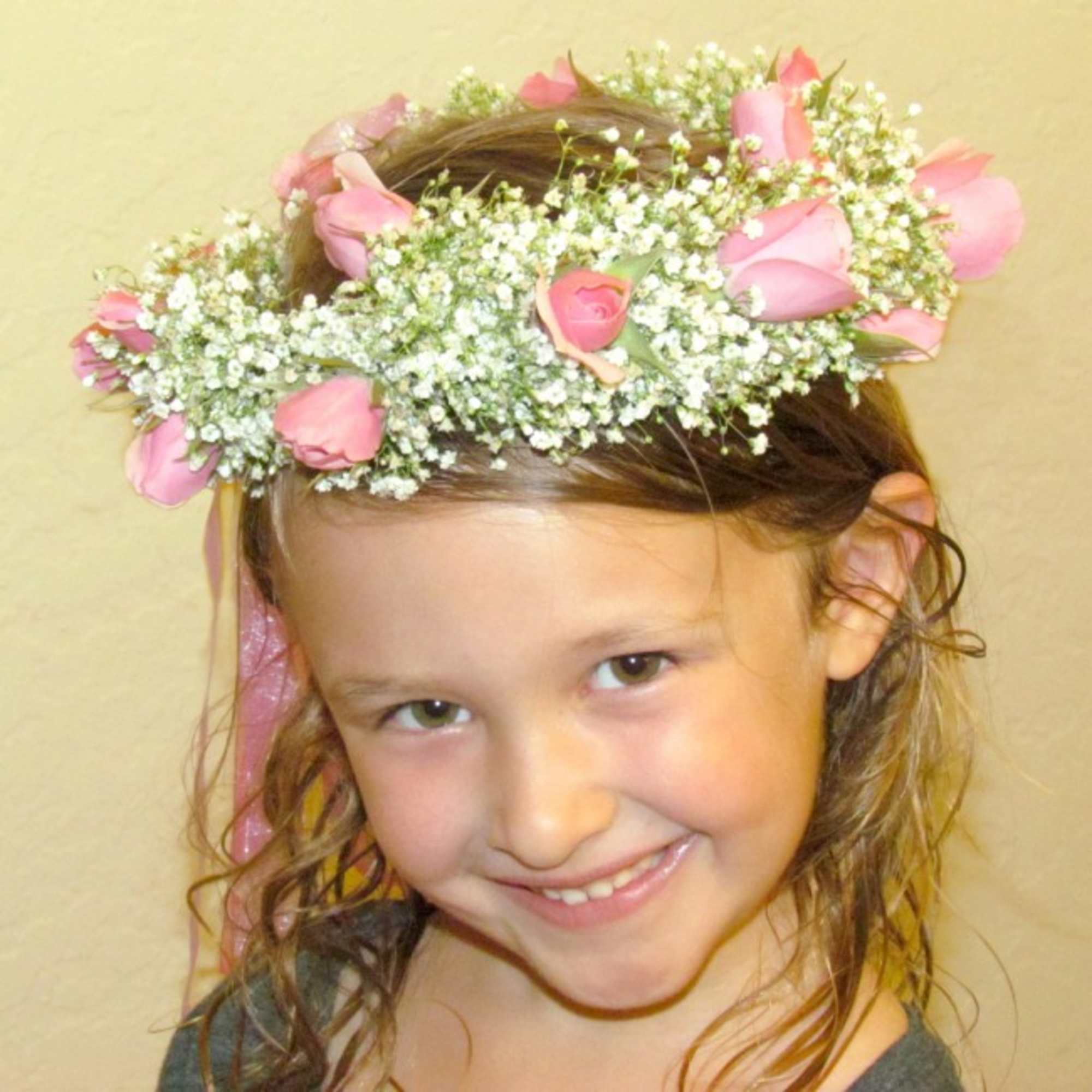 Girl wearing a pink rose and baby's breath flower crown