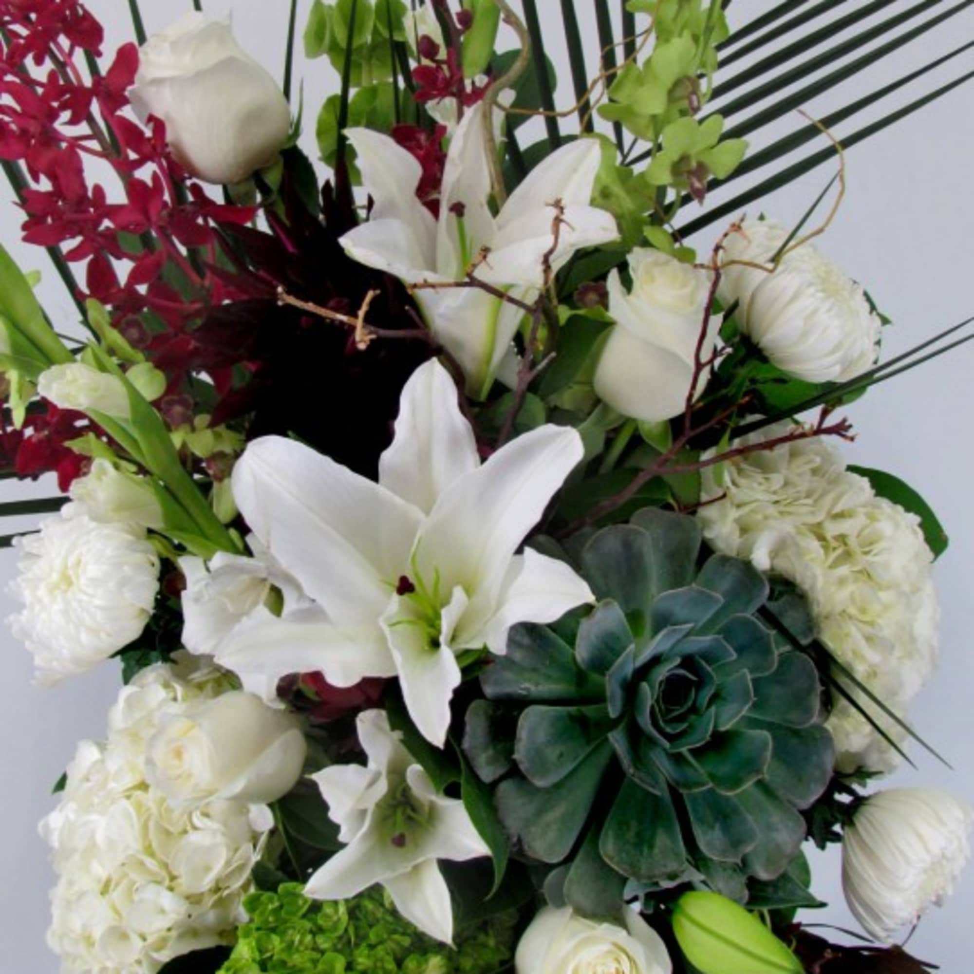 Tall bouquet of white lilies, roses, and hydrangeas with green succulents