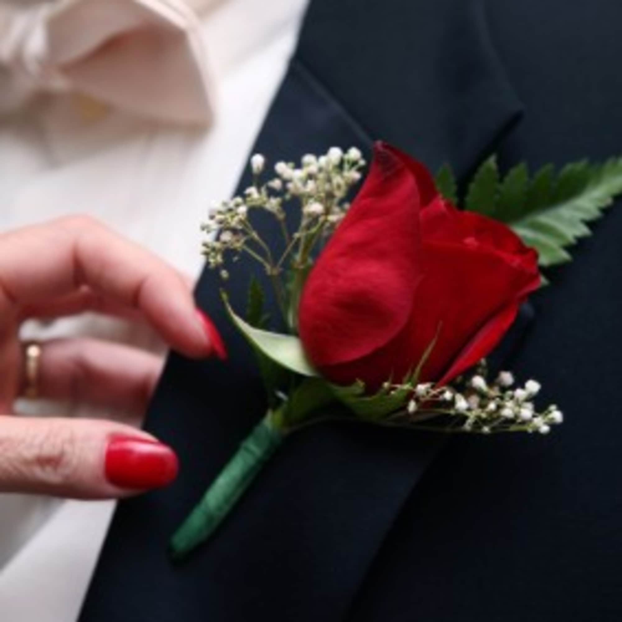 Red rose boutonniere pinned to a dark suit jacket