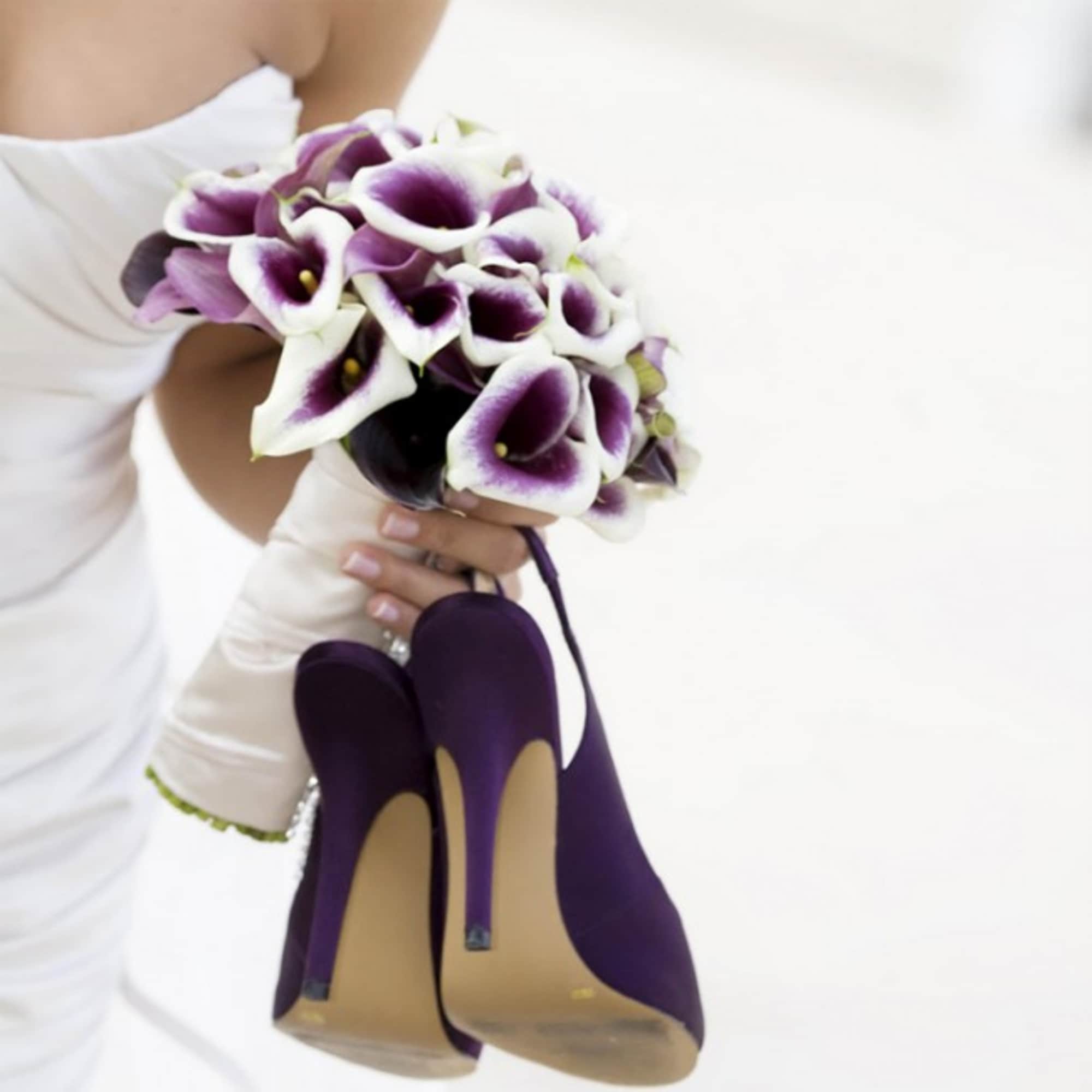 Bride holding a bouquet of purple and white calla lilies with purple high heels attached