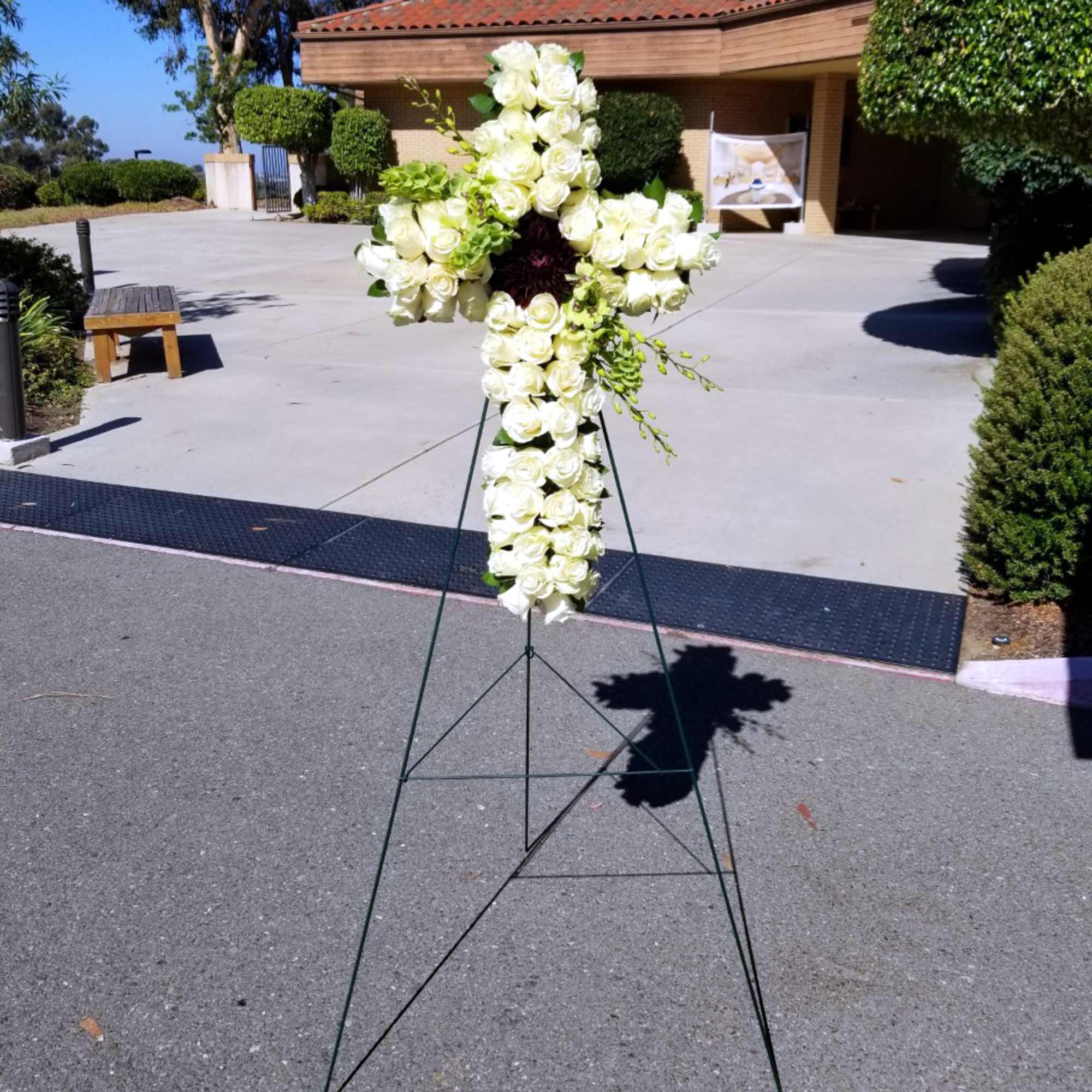 White rose cross-shaped floral standing spray on an easel