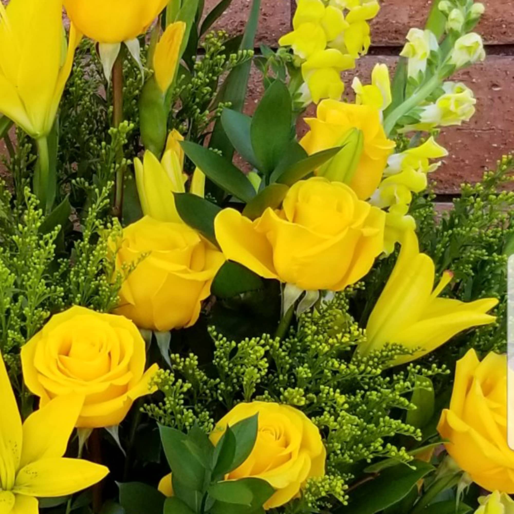 Yellow roses and snapdragons arranged with greenery