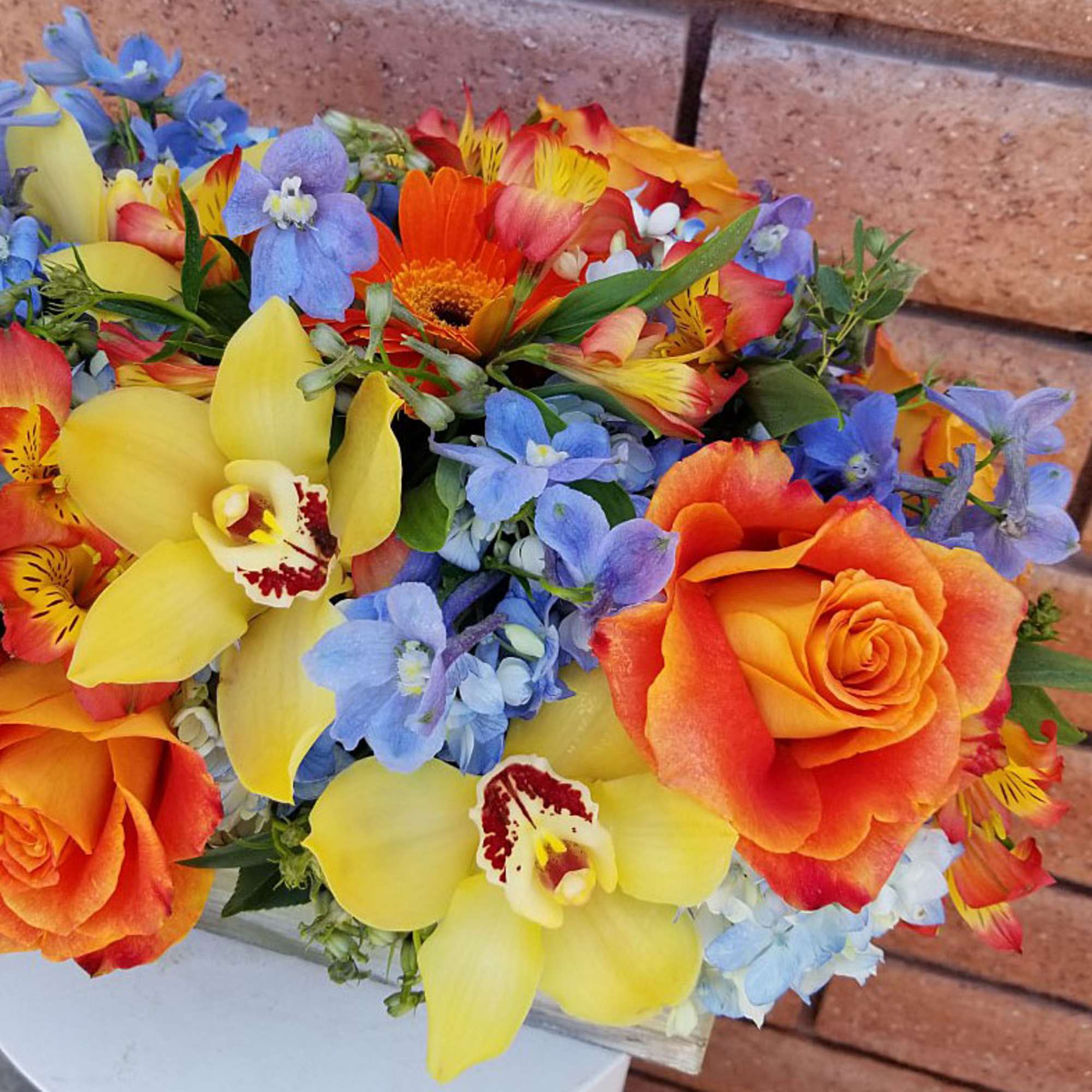 Bouquet of orange roses, yellow orchids, and blue flowers