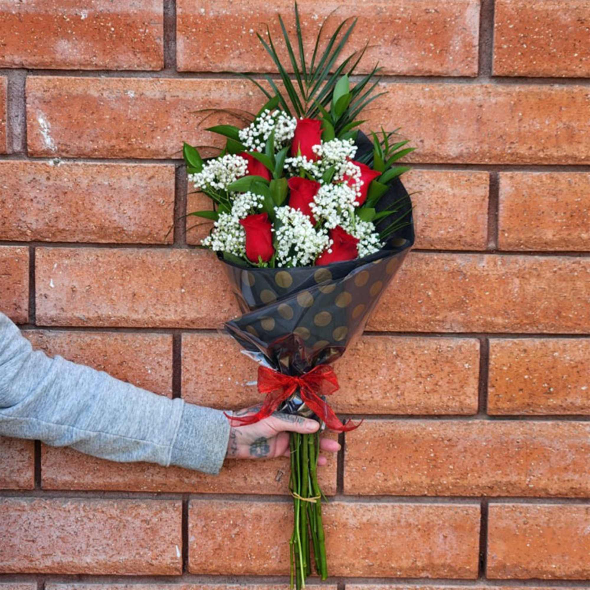 Bouquet of red roses and white baby's breath wrapped in black paper