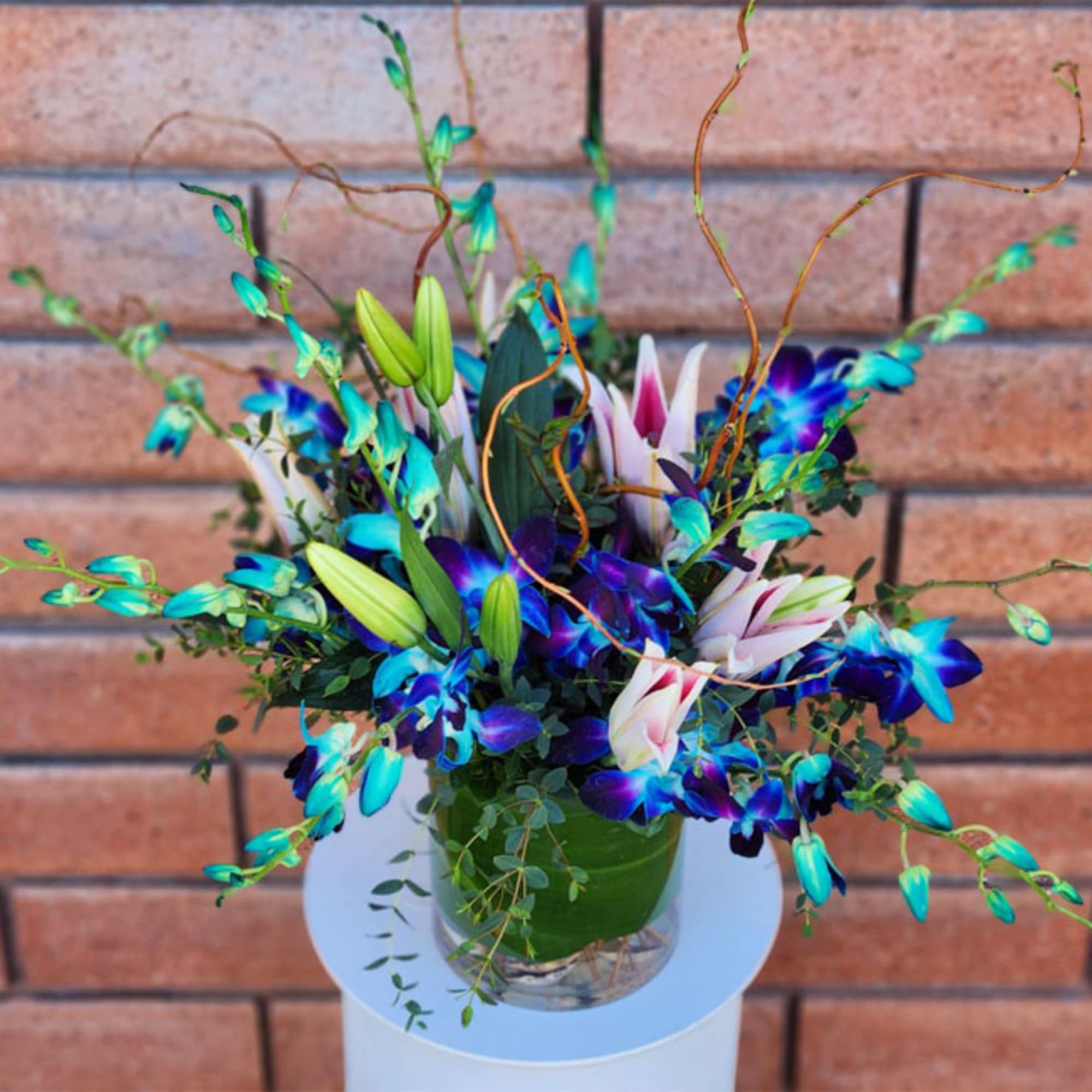 Blue and white lily arrangement in a glass vase