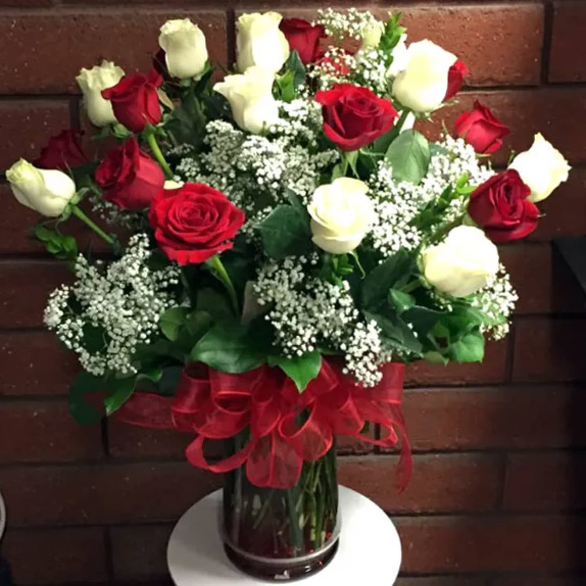 Bouquet of red and white roses in a glass vase with a red ribbon