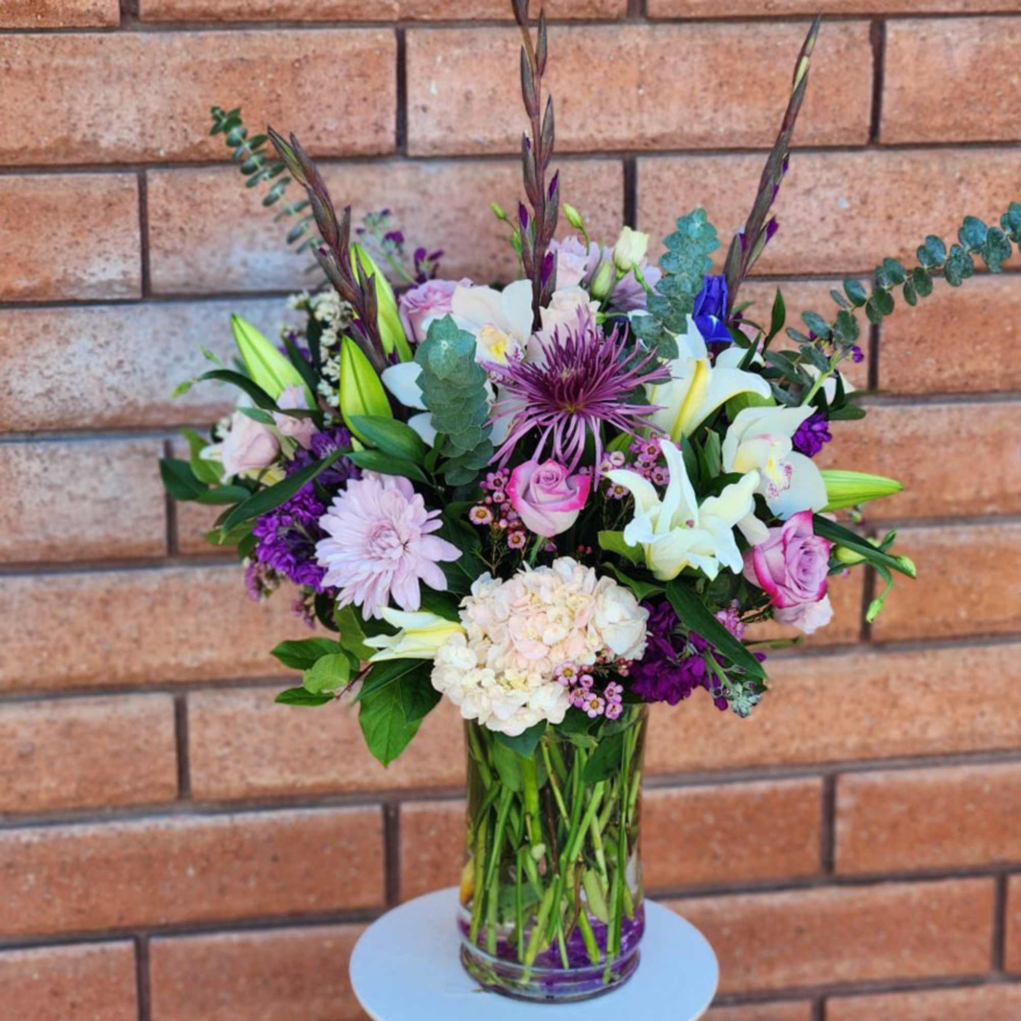 Mixed bouquet of lilies, roses, and hydrangea in a clear glass vase