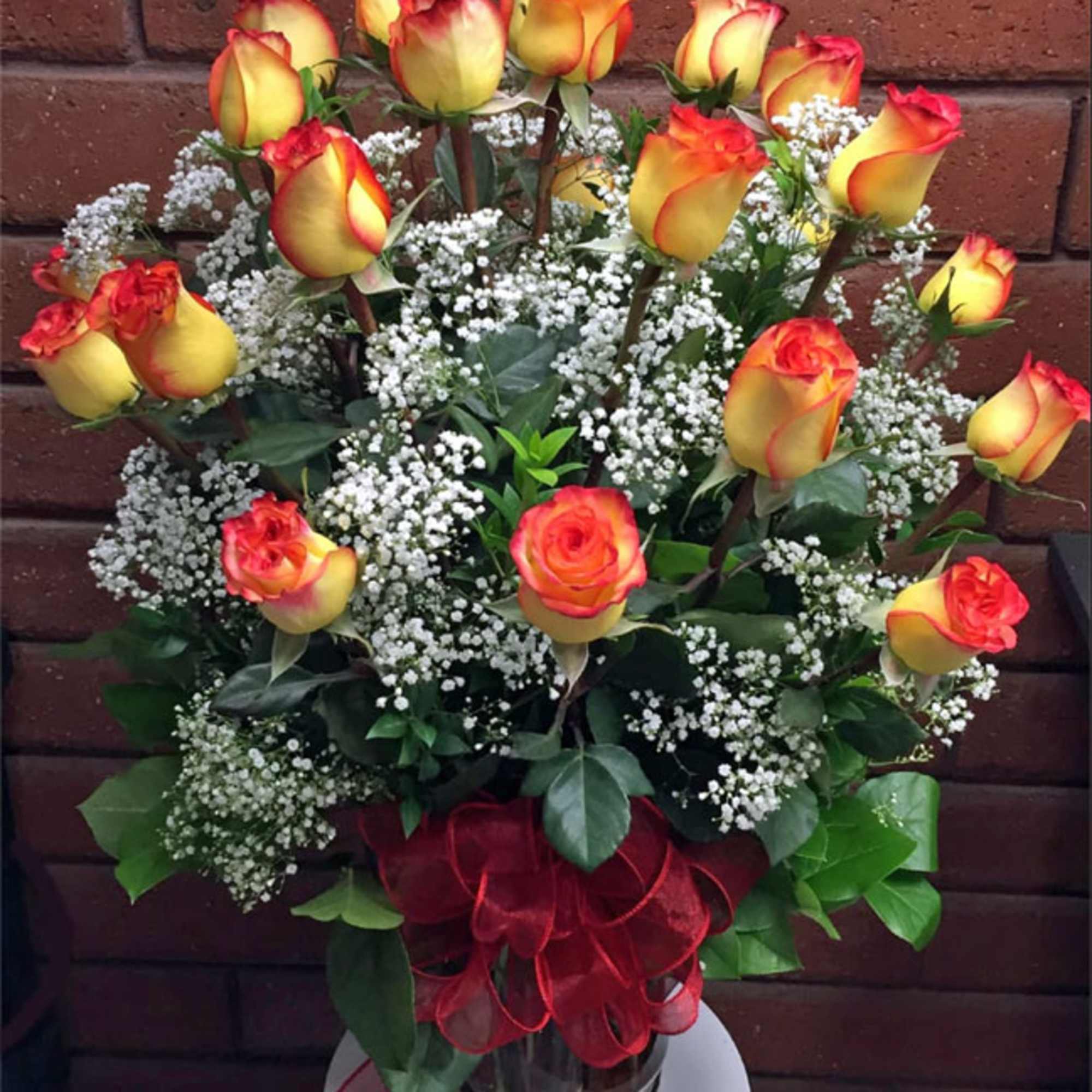 Bouquet of yellow and red roses with baby's breath in a glass vase