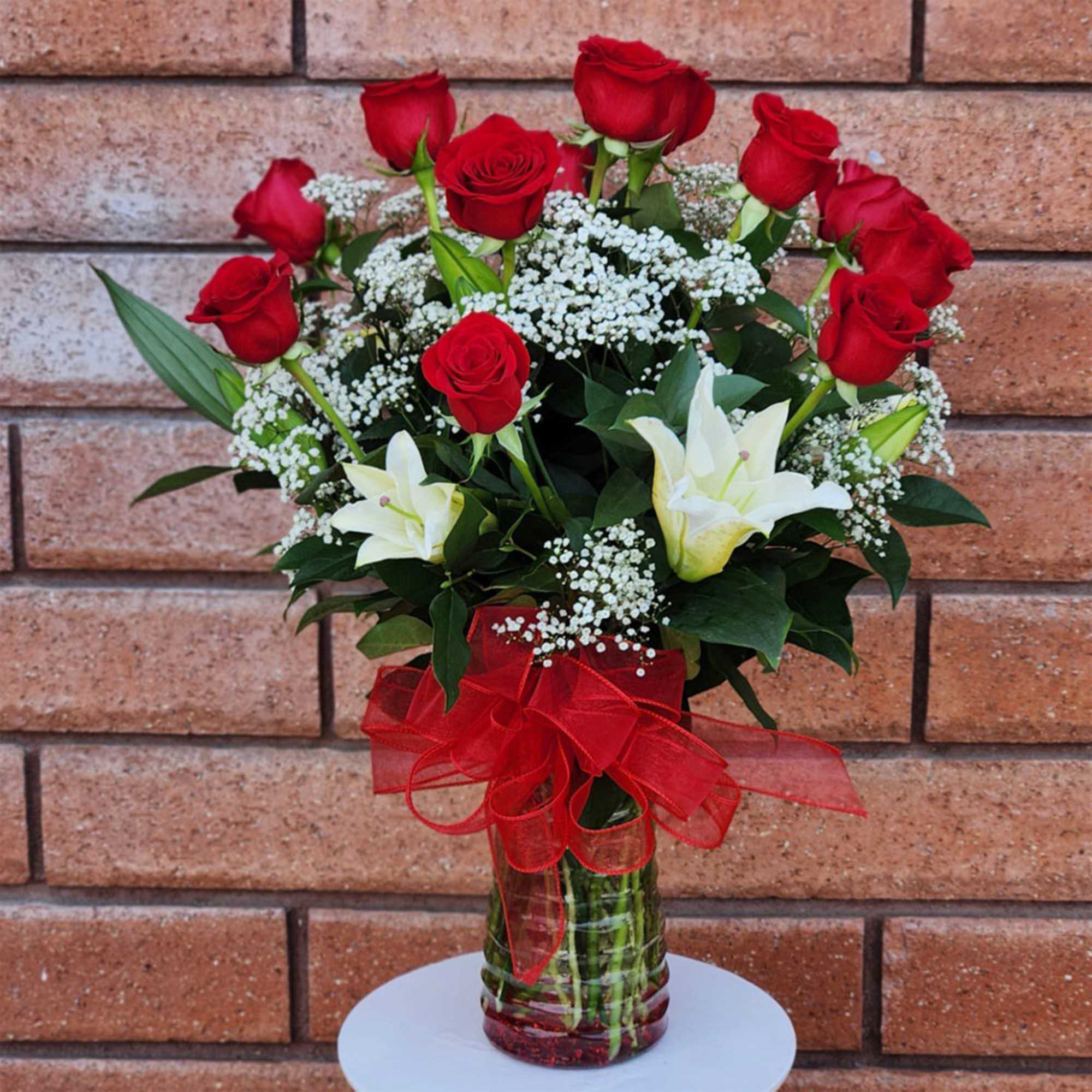 Red roses and white lilies in a glass vase with a red ribbon