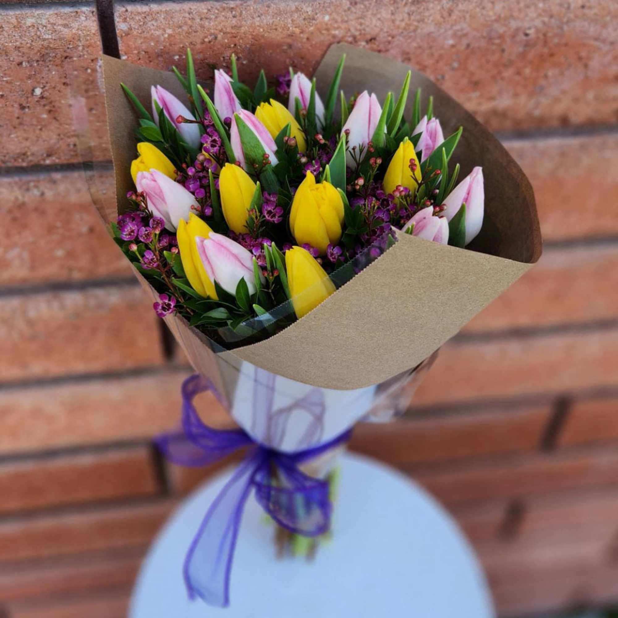 Bouquet of yellow and pink tulips wrapped in brown paper