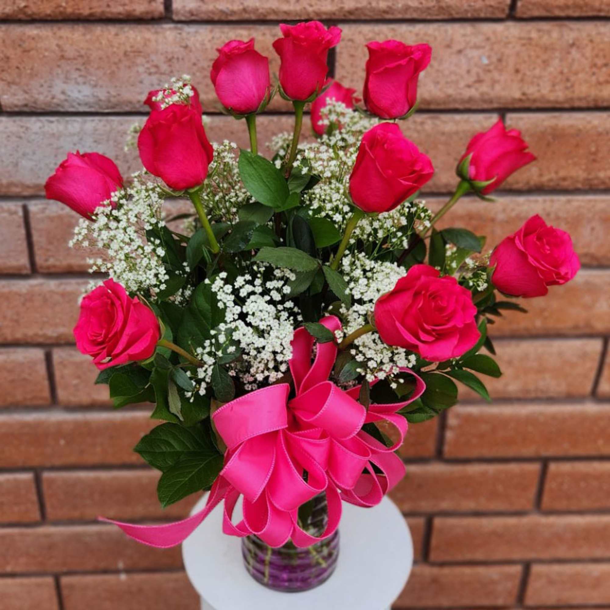 Pink roses in a glass vase with baby's breath and a pink ribbon