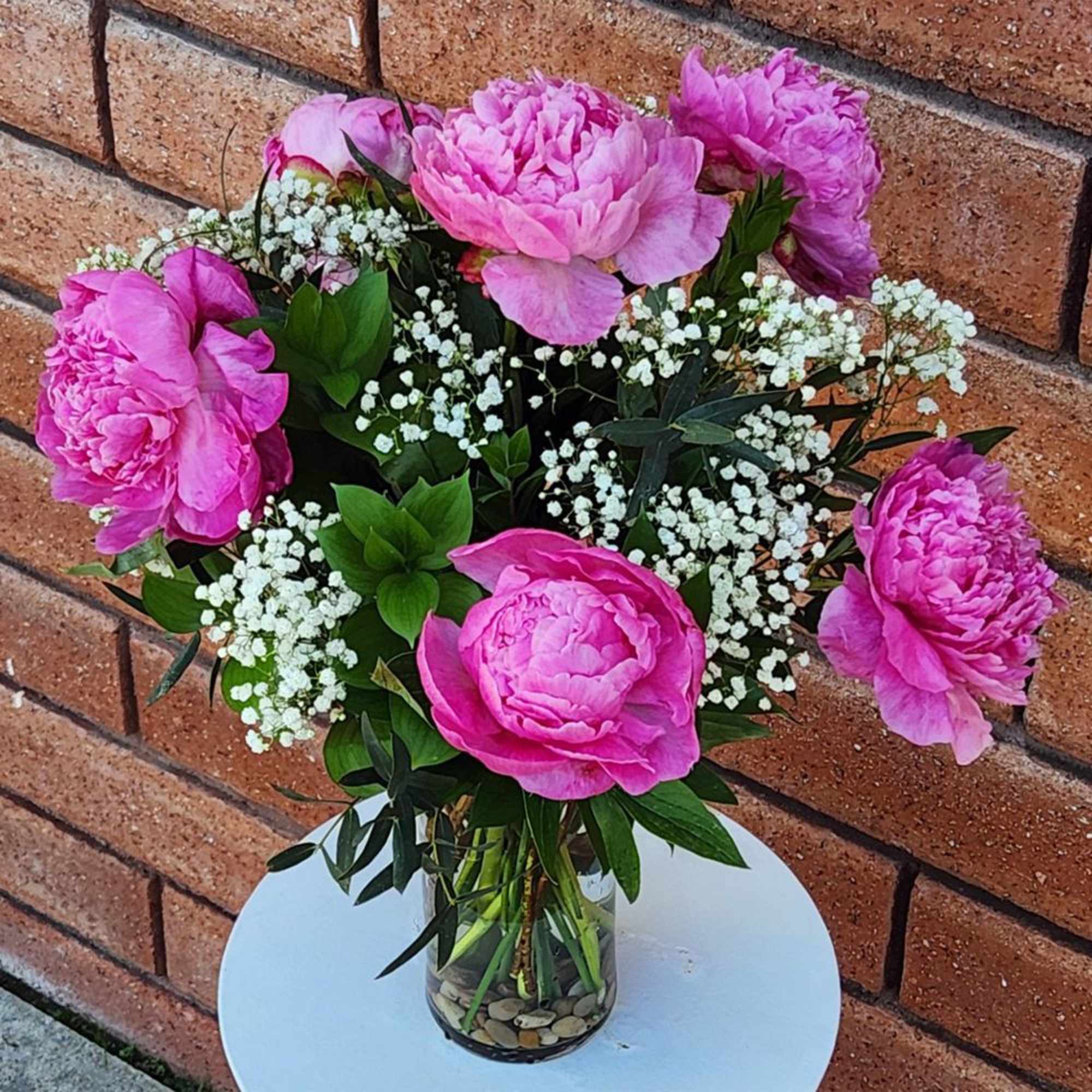 Pink peonies and baby's breath in a clear glass vase