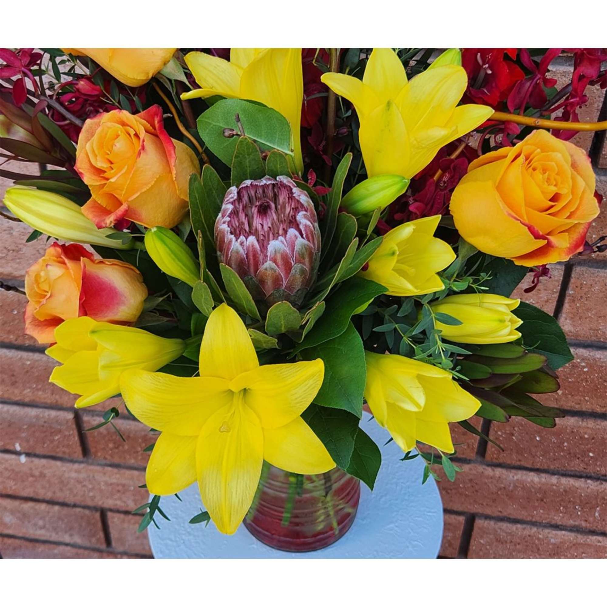 Bouquet of yellow lilies and orange roses in a glass vase