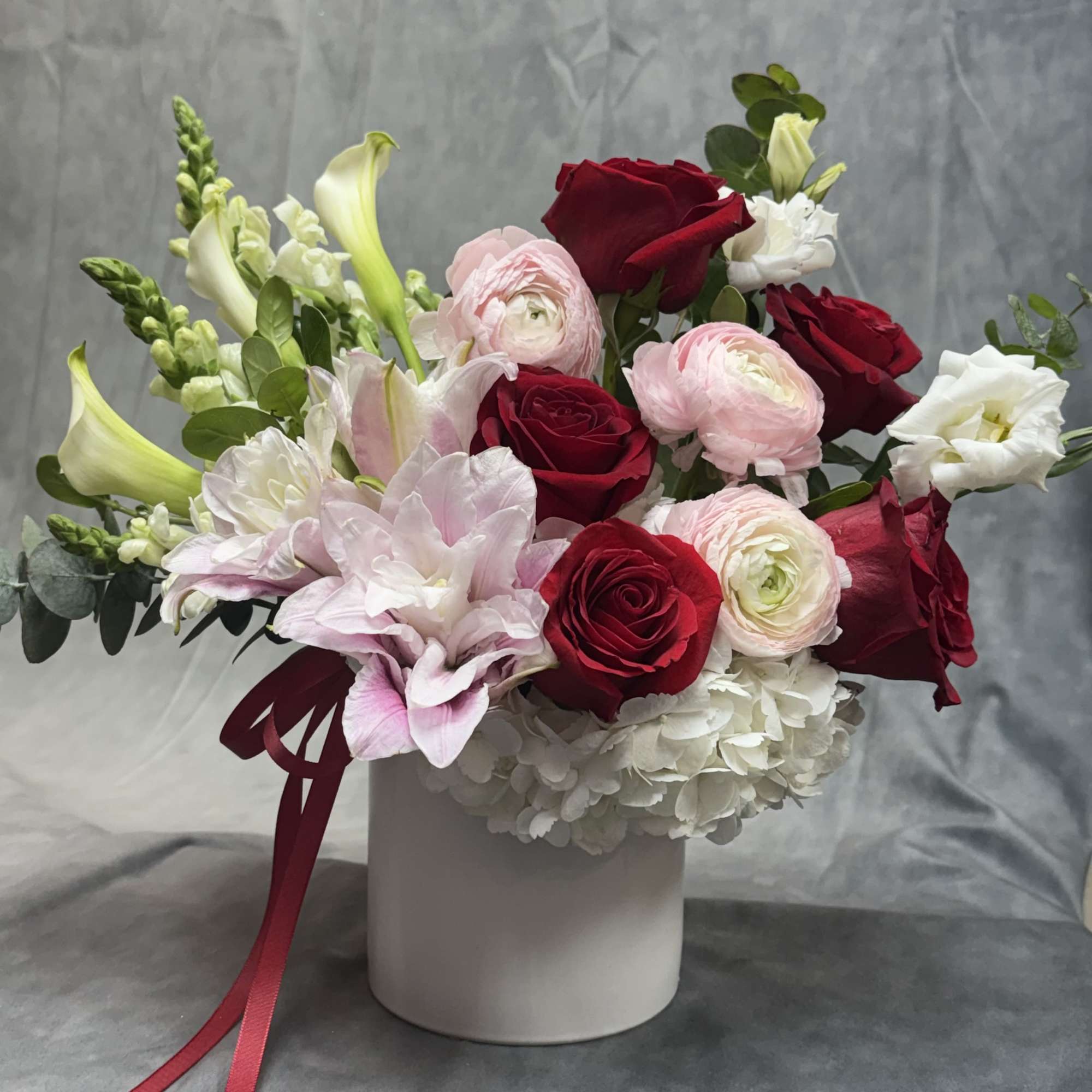 Bouquet of red and pink roses with white blooms in a white vase
