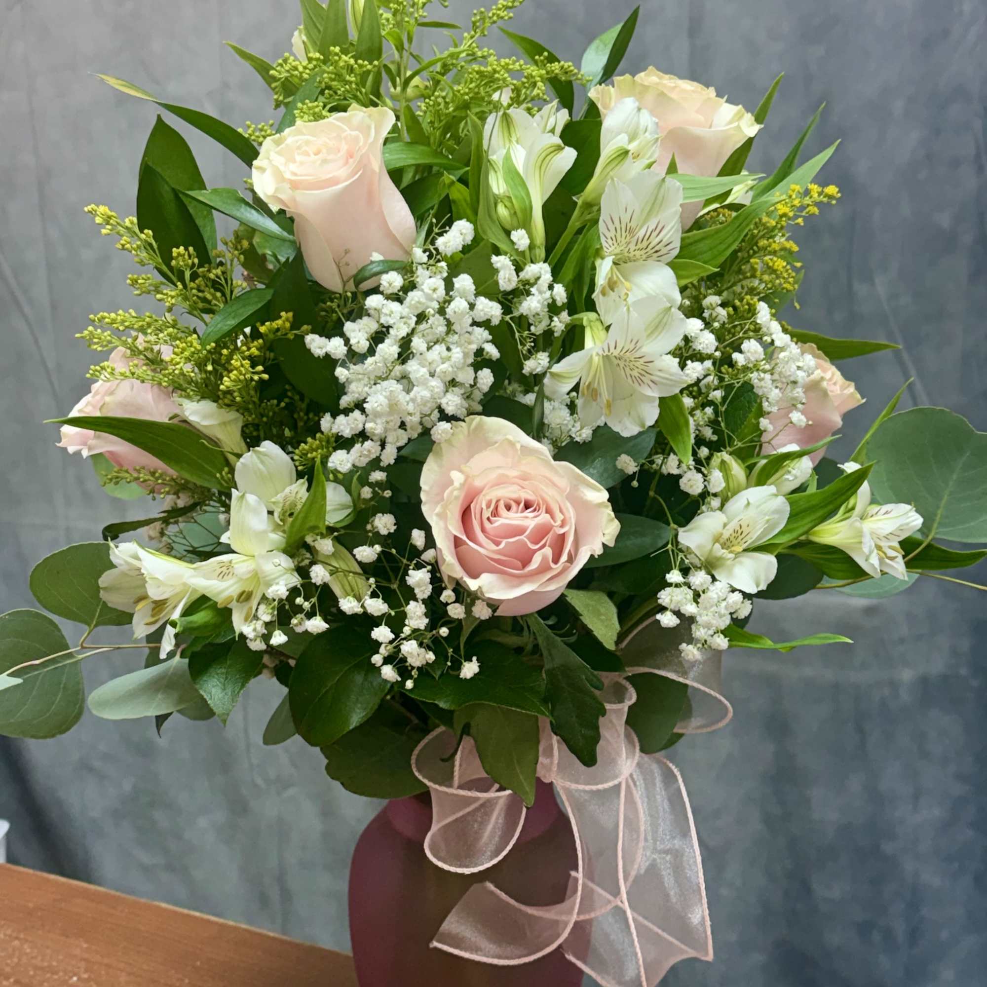 Pink roses and white blooms in a pink frosted vase with a sheer ribbon bow