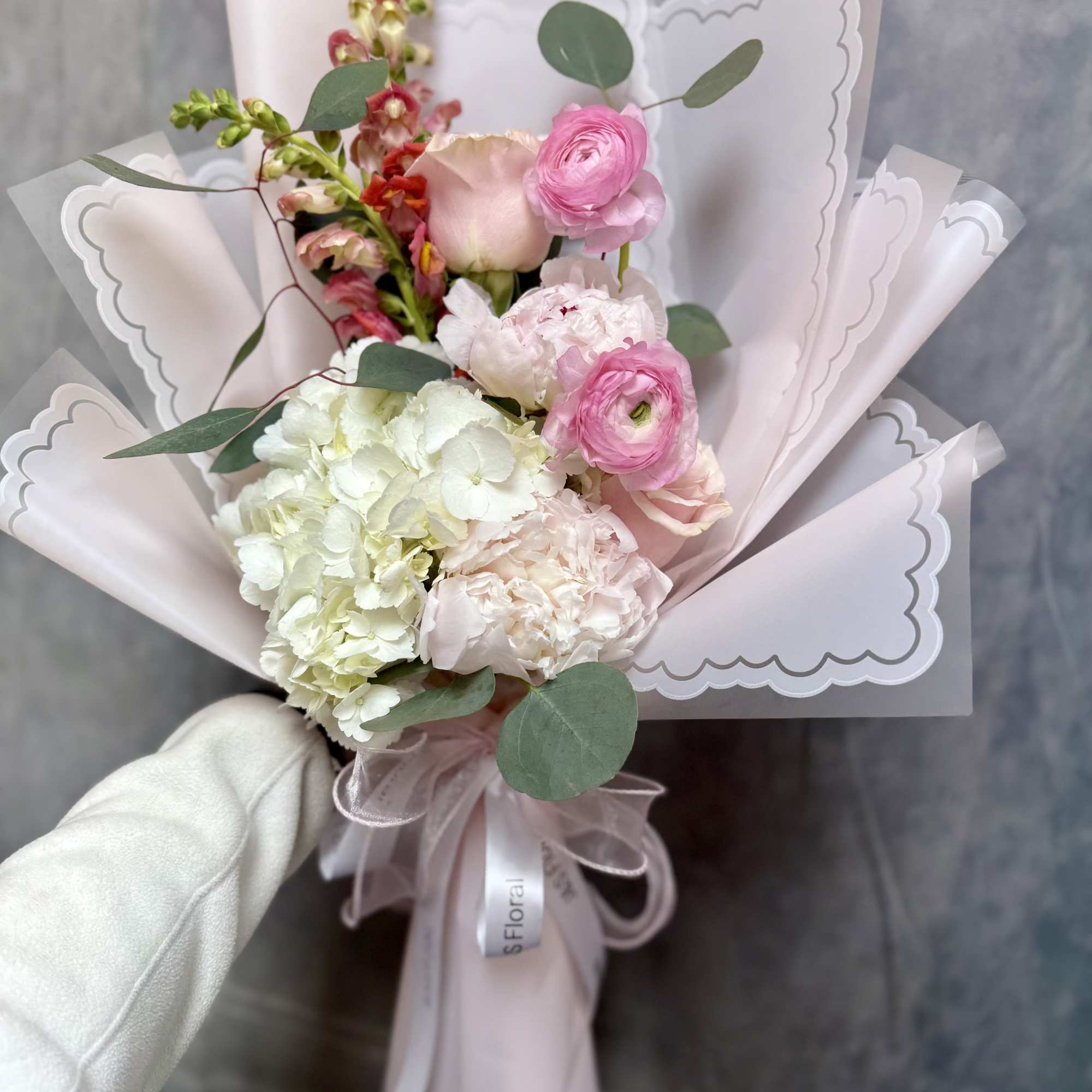A romantic hand- tied bouquet of elegant soft blooms, hydrangeas, snapdragon and