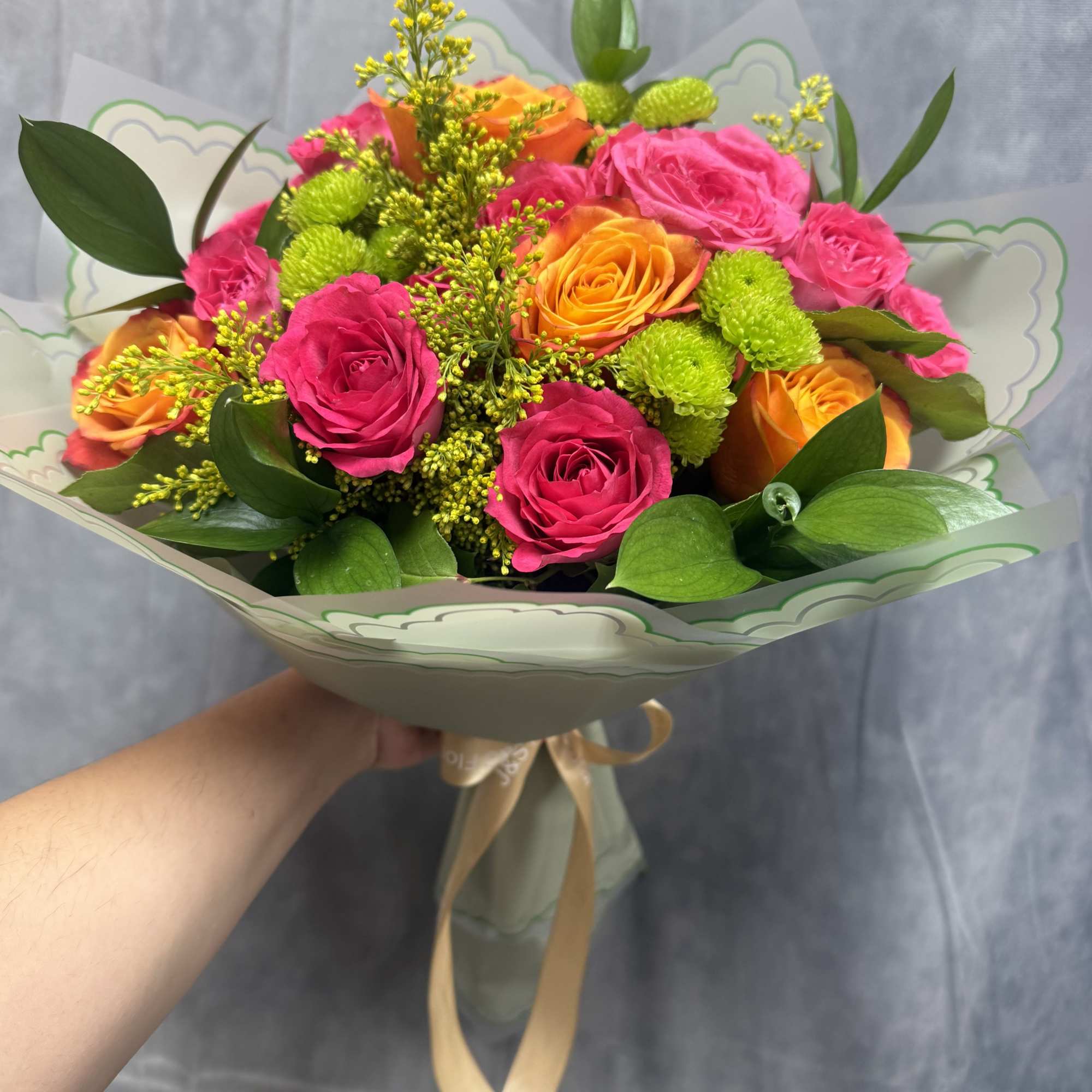 A vibrant mix of hot pink and orange roses accented with cheerful