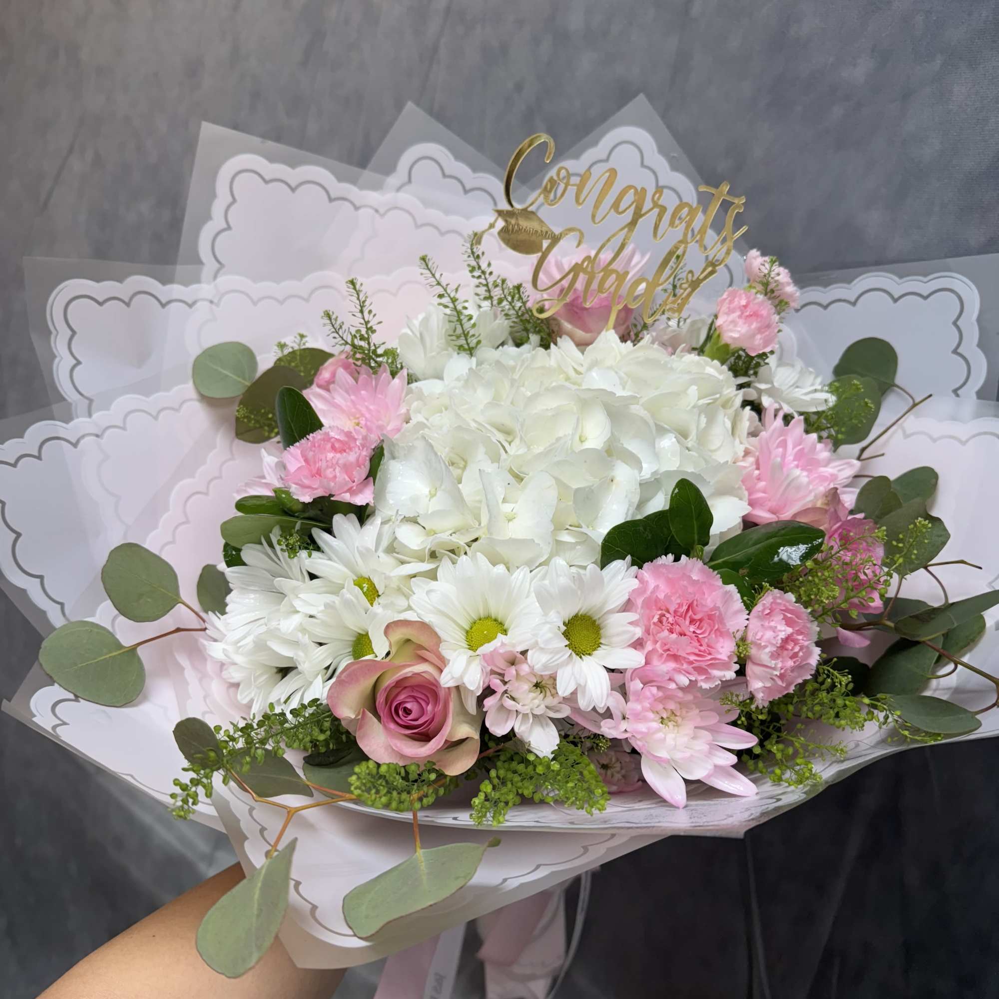 Pink and white bouquet with a gold "Congrats Grad" topper