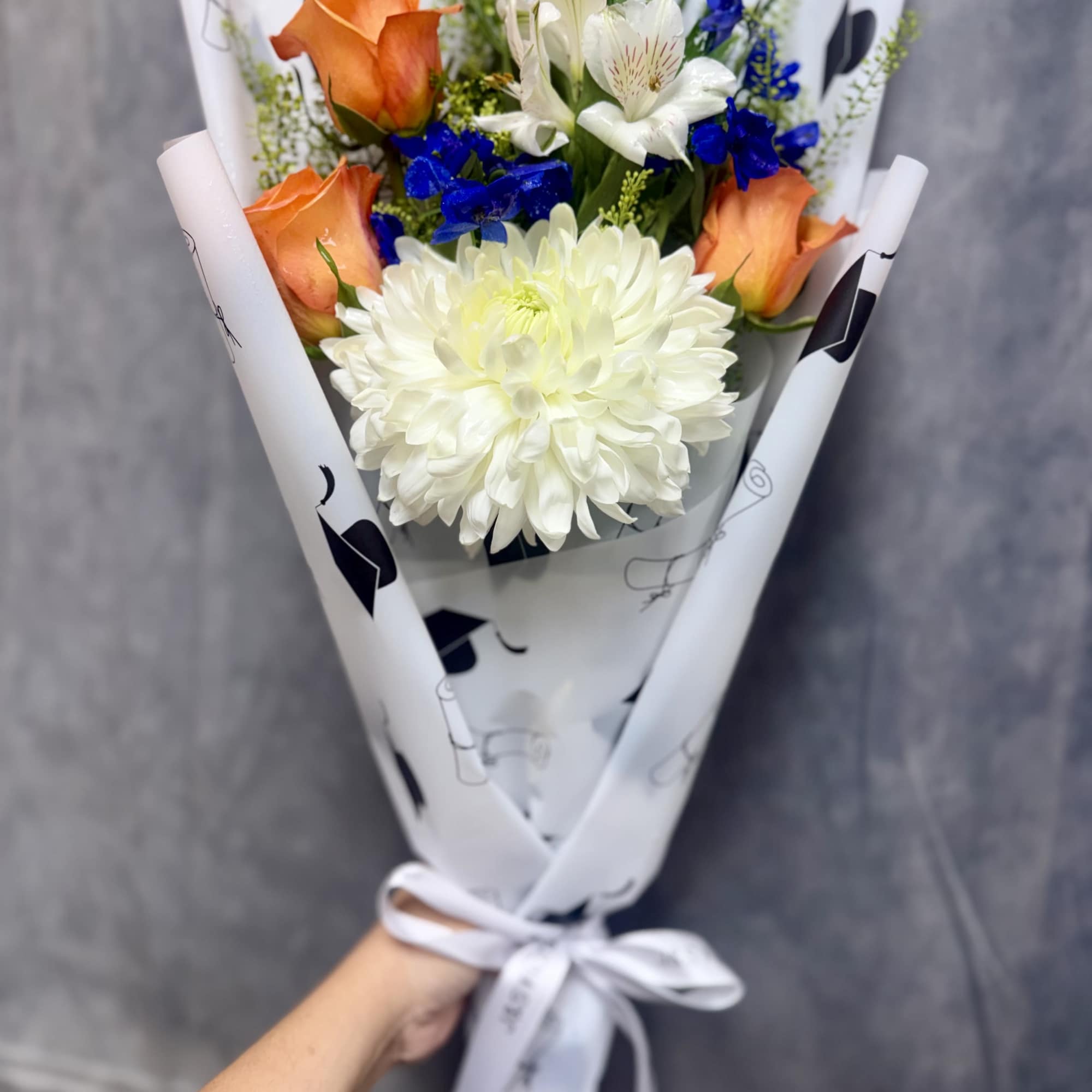 Bright orange roses with a large white chrysanthemum and vivid blue accents, photo 2 of 3