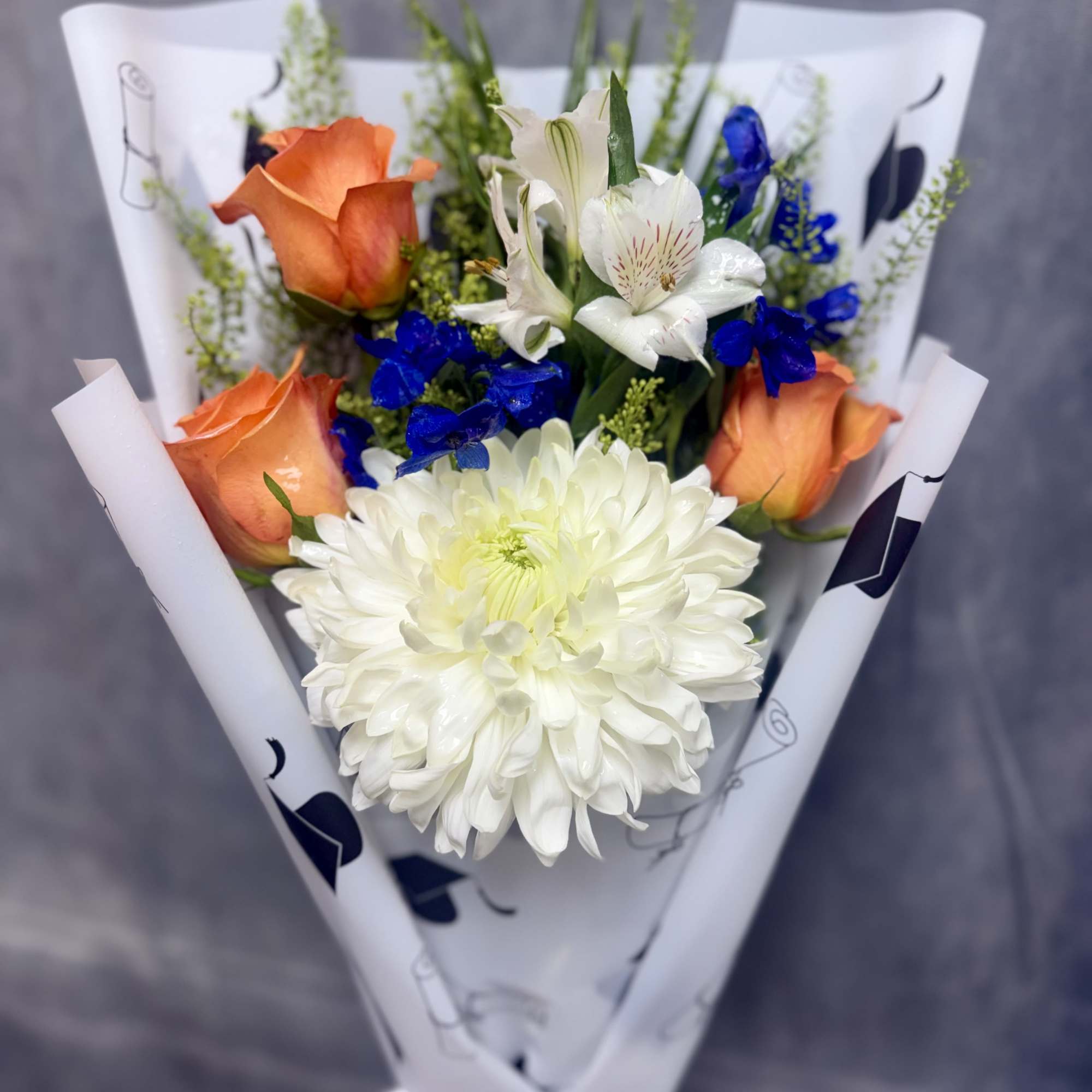 Bright orange roses with a large white chrysanthemum and vivid blue accents, photo 3 of 3