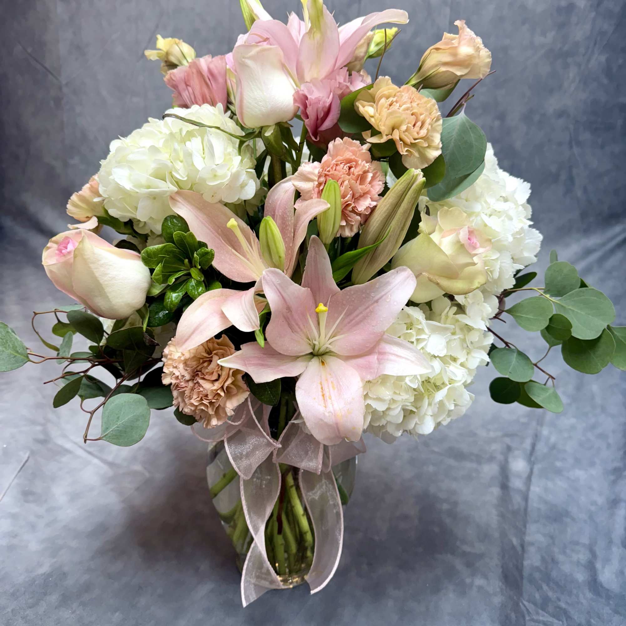 Pink lilies and white hydrangeas in a glass vase with a ribbon, photo 2 of 2