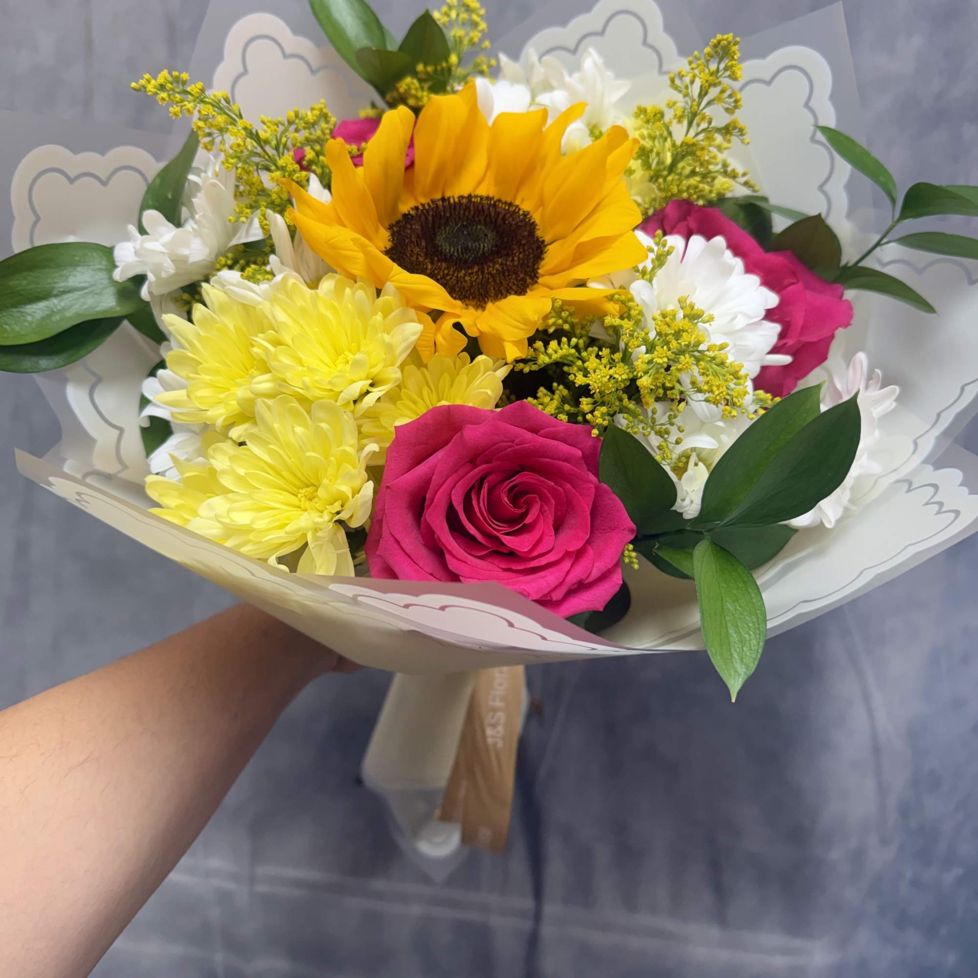 Bursting with cheerful color, this vibrant bouquet features a radiant sunflower, hot