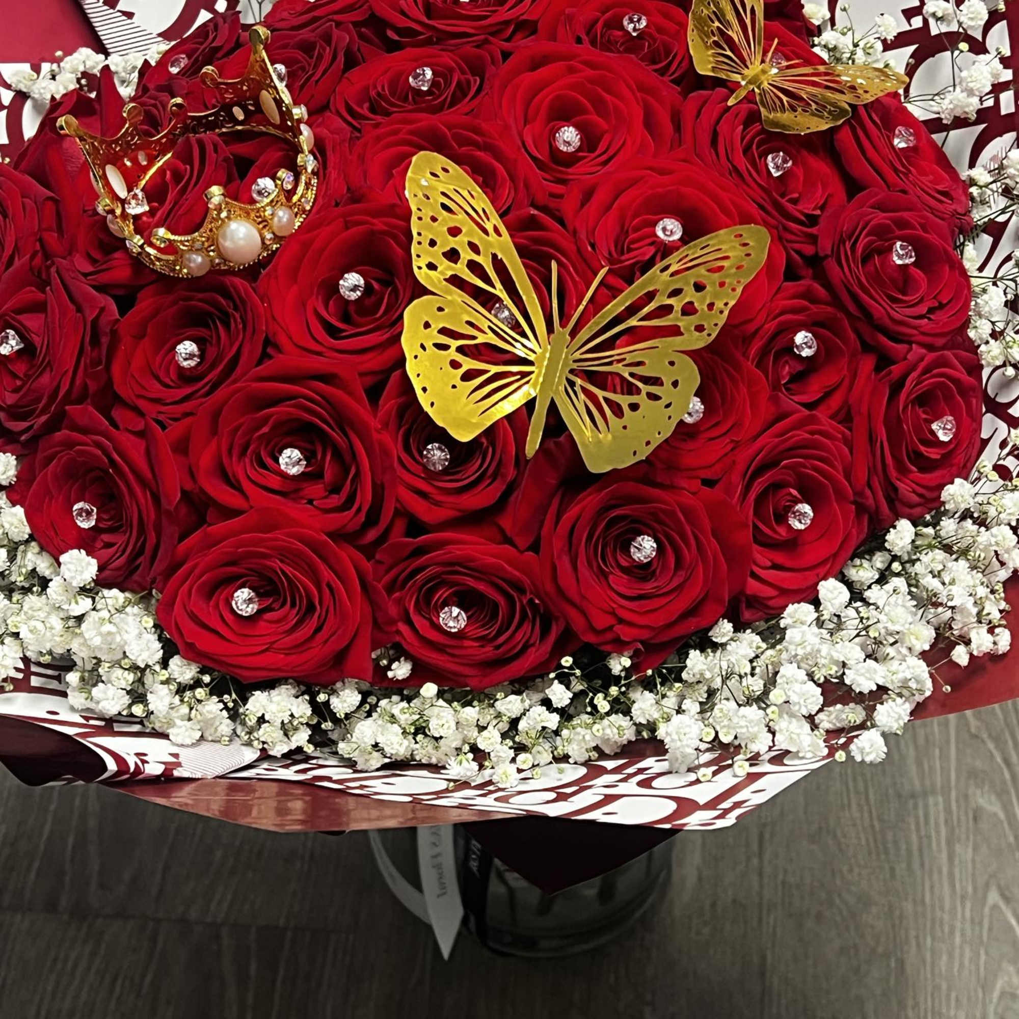 Red rose bouquet with white baby's breath, gold butterflies, and a jeweled crown