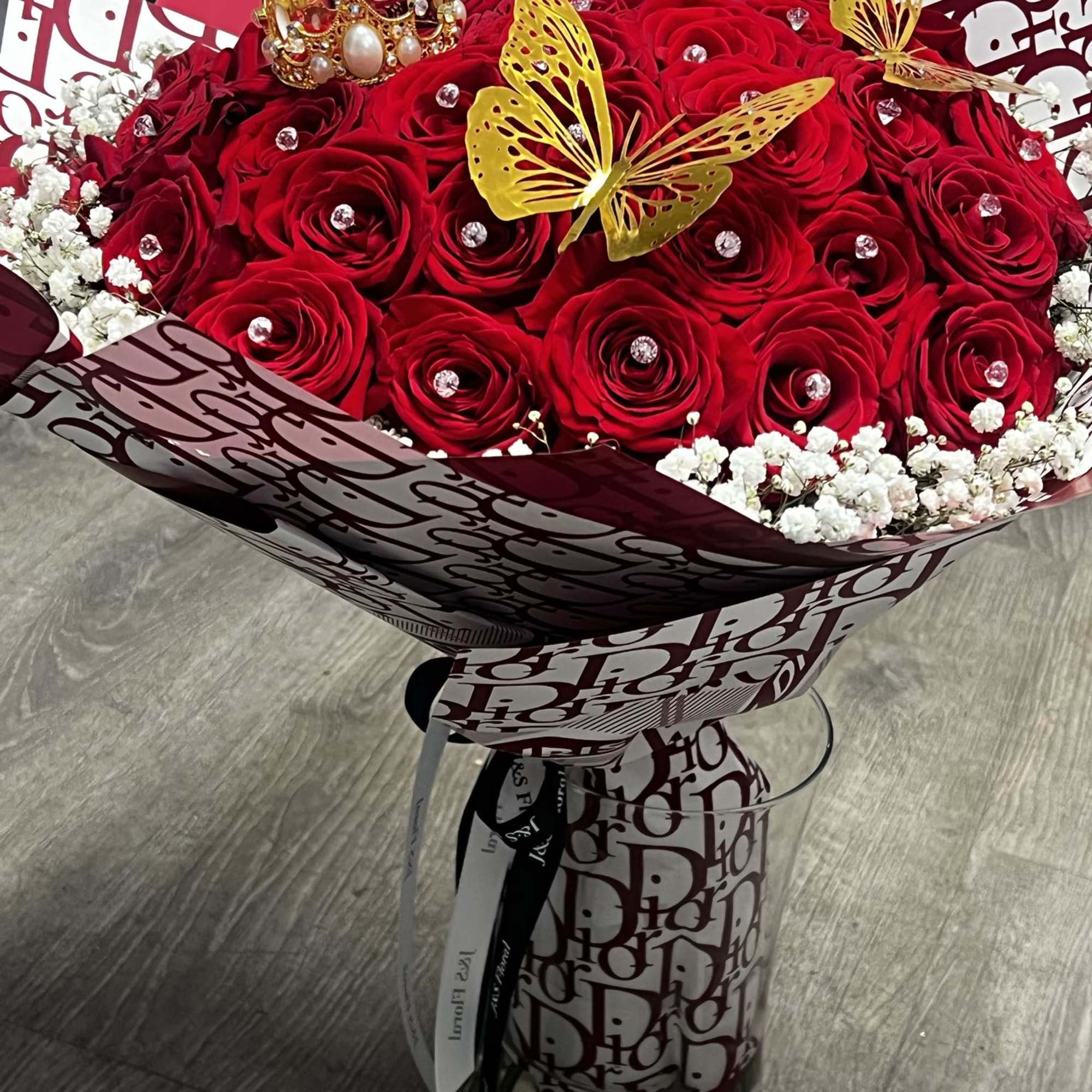 Red rose bouquet with white baby's breath in decorative wrap and a clear vase