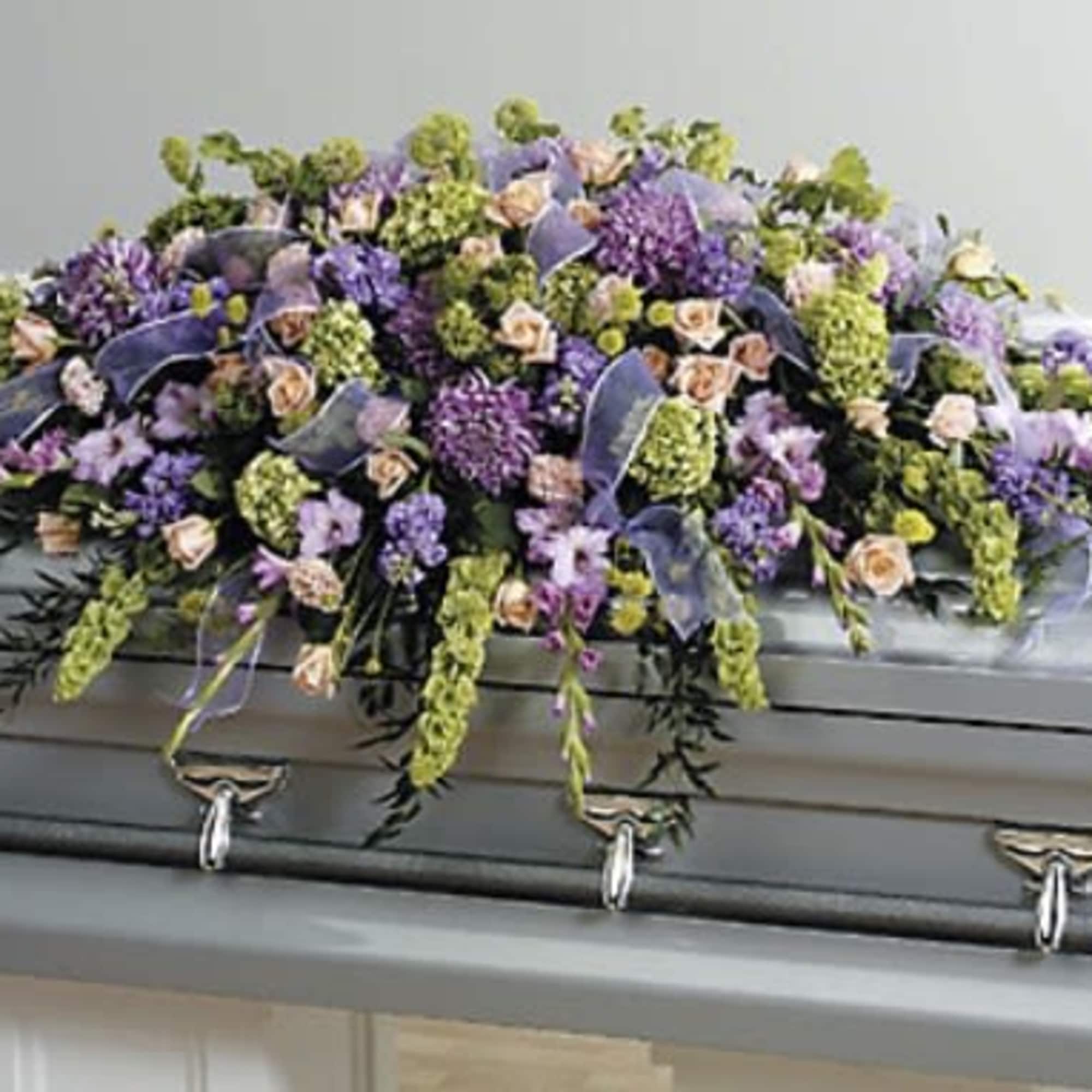 Purple and green floral spray on a gray casket
