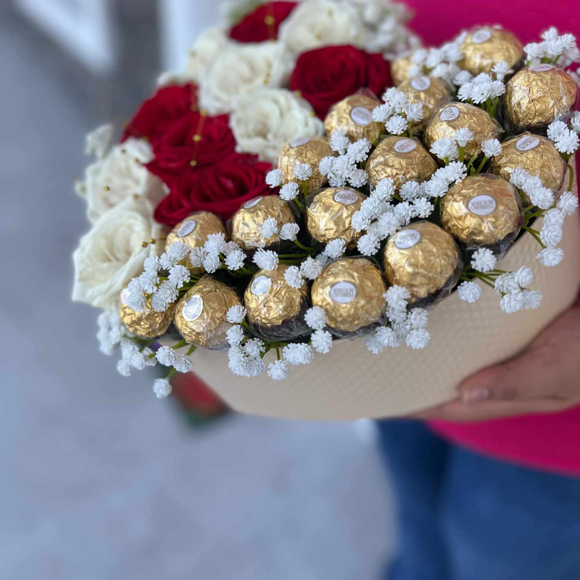 Bouquet of red and white roses with gold-wrapped chocolates in a beige box